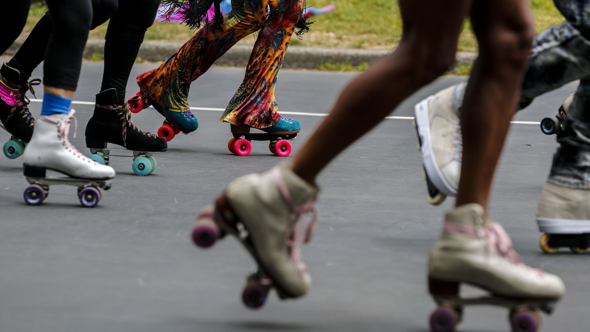 People in skates on a concrete street wearing colorful pants and socks