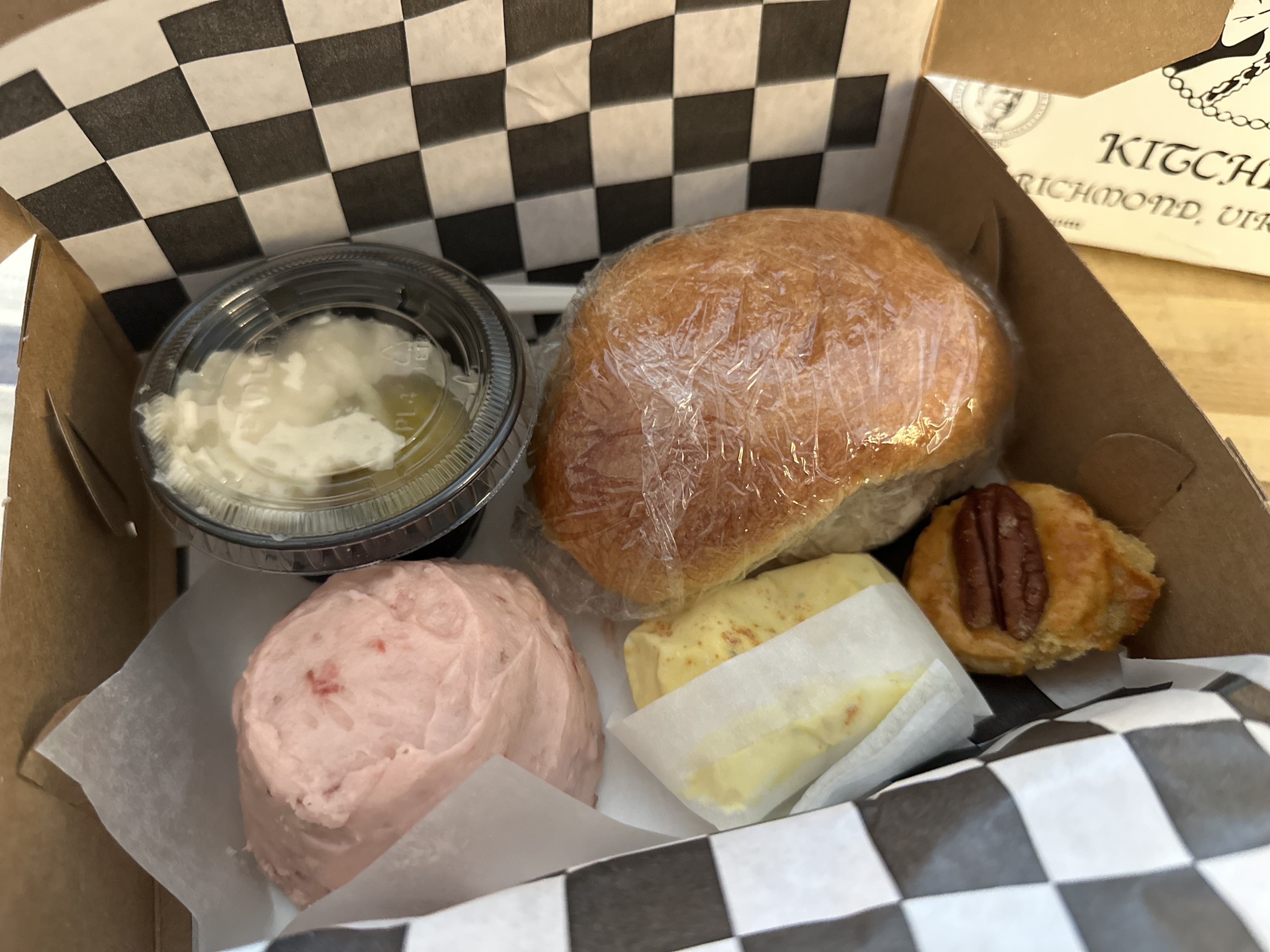 A box with a roll, cupcake, potato salad, cookie and deviled egg