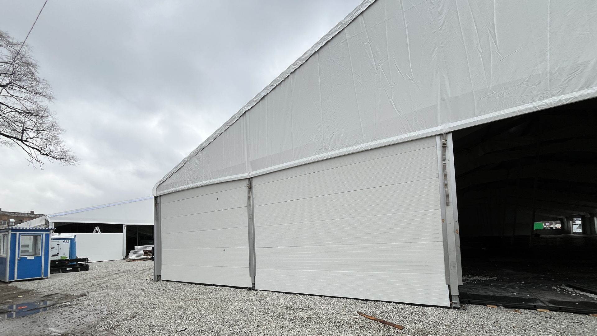Two giant white tent constructed on gravel in Brighton Park.