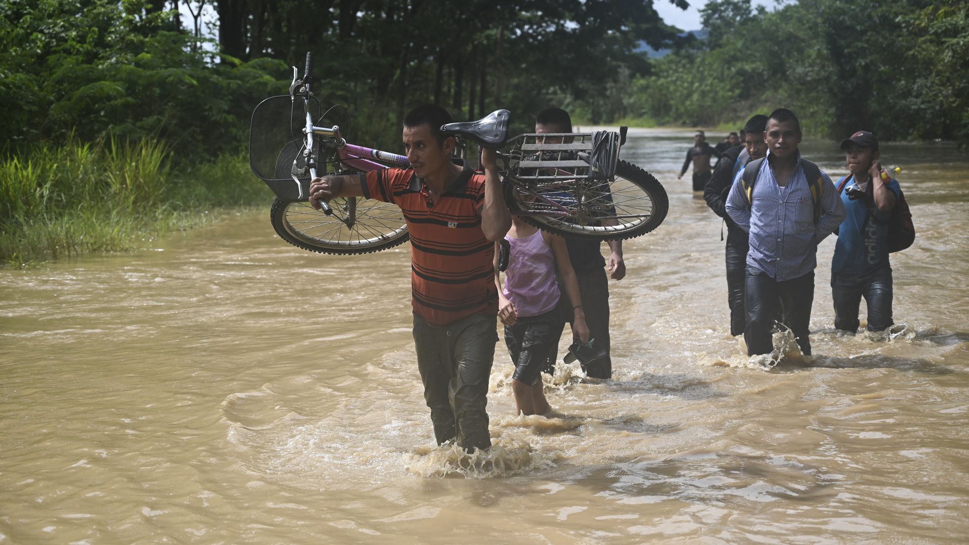 People wade through the water in a flooded area in Panzos, Alta Verapaz, 220 km north of Guatemala City on November 6, 2020 after the passage of Hurricane Eta -now degraded to a tropical storm.