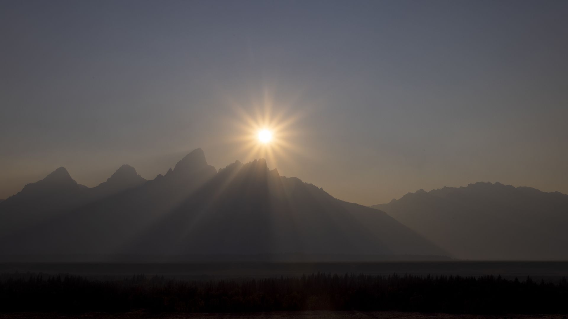 The sun sets behind the Grand Teton peak, shrouded in smoke from regional wildfires July 14, 2021 at Grand Teton National Park.