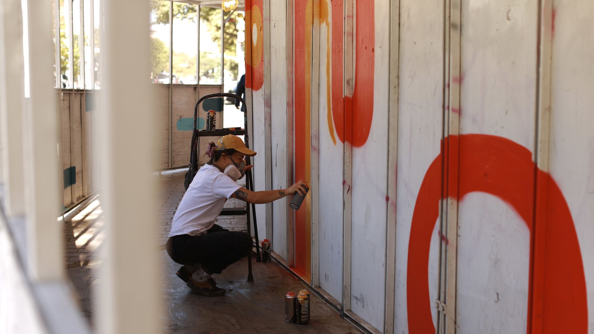 A photo of an artist spraying a wall.