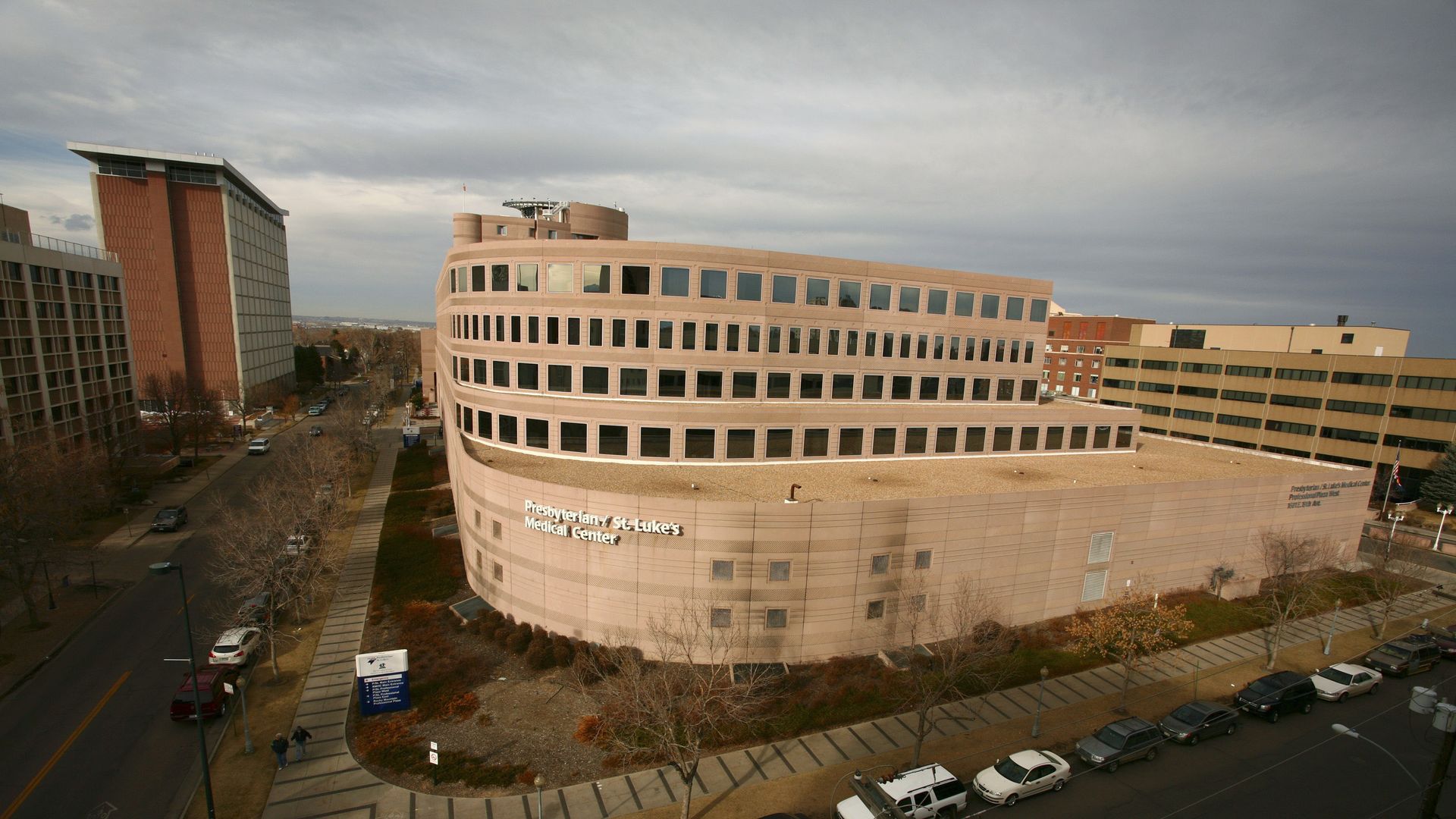 A light brown hospital building at the corner of an intersection.