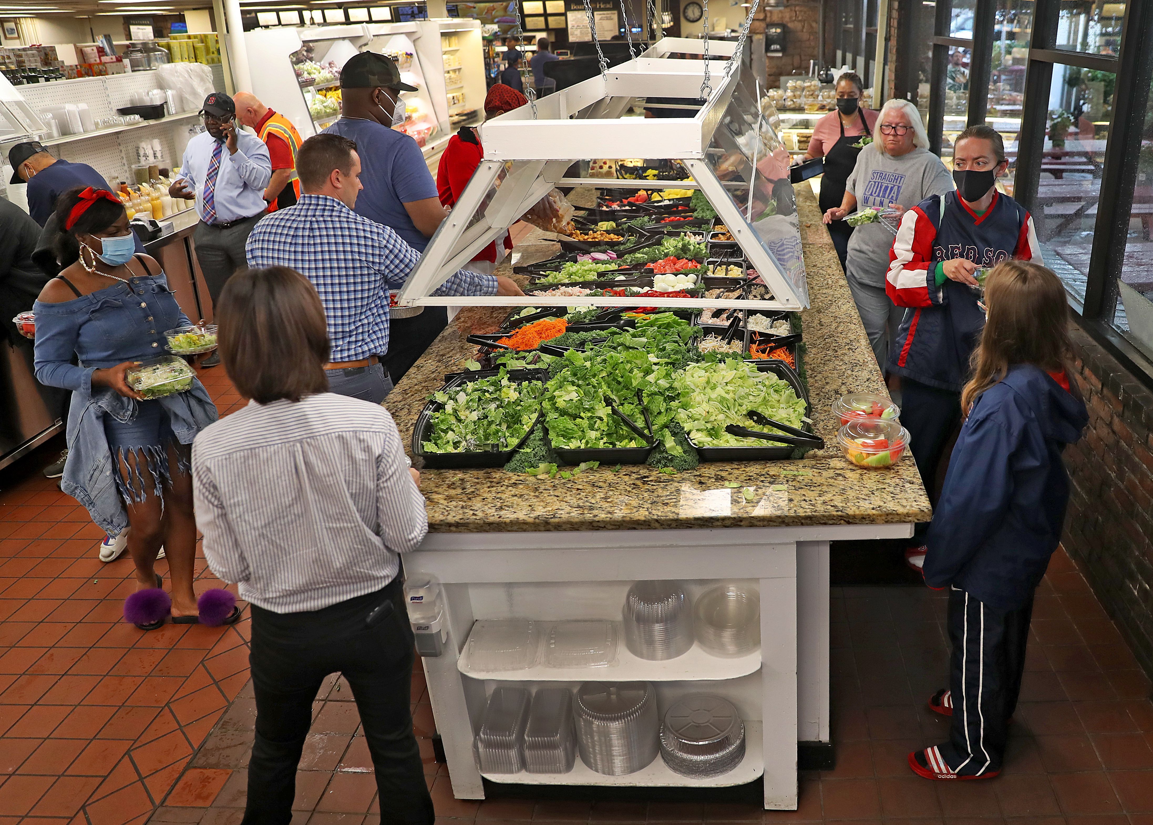 People enjoy the opening of the salad bar at Lambert's Market in Boston's Dorchester after the easing of coronavirus restrictions in Massachusetts on June 14. 