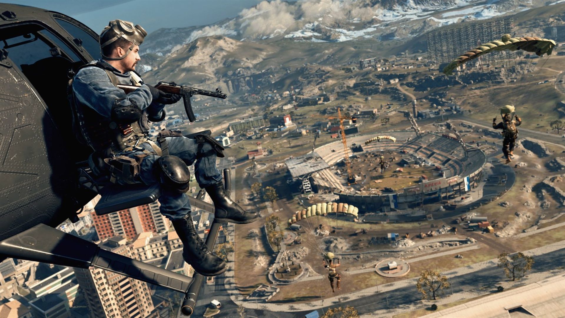 Video game screenshot of a soldier sitting on the side of a military helicopter as it flies over a city