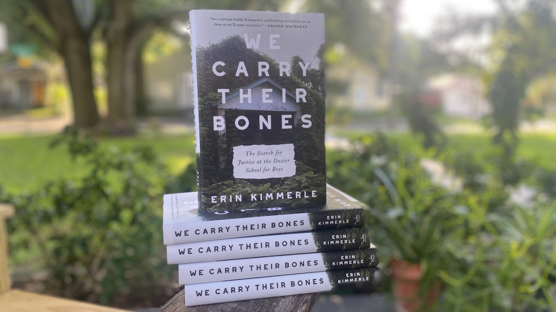 A photo of five "We Carry Their Bones" books stacked on top of each other.