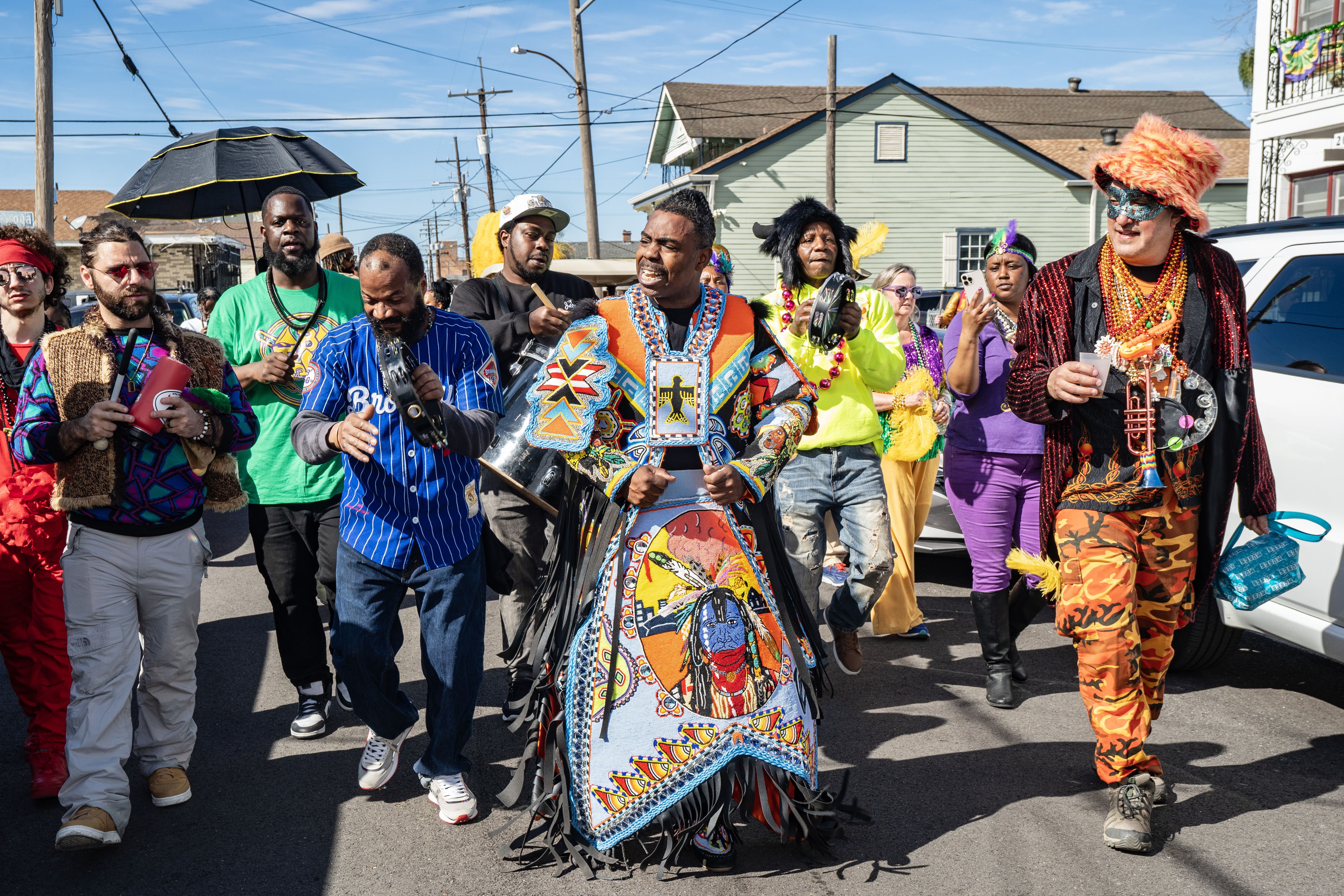 Photo shows a Mardi Gras Indian in a colorful feathered suit