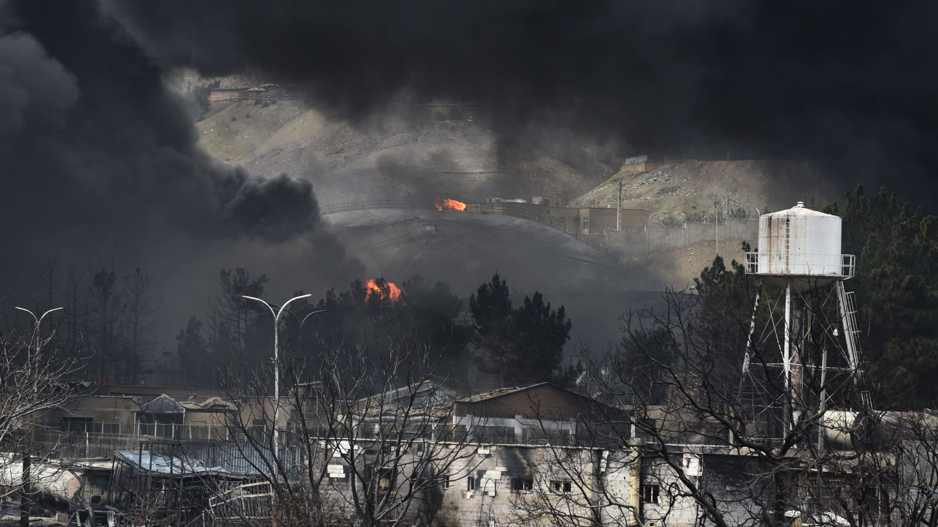 Thick black smoke billows over oil storage tanks and industrial buildings in Tehran following reported overnight airstrikes.