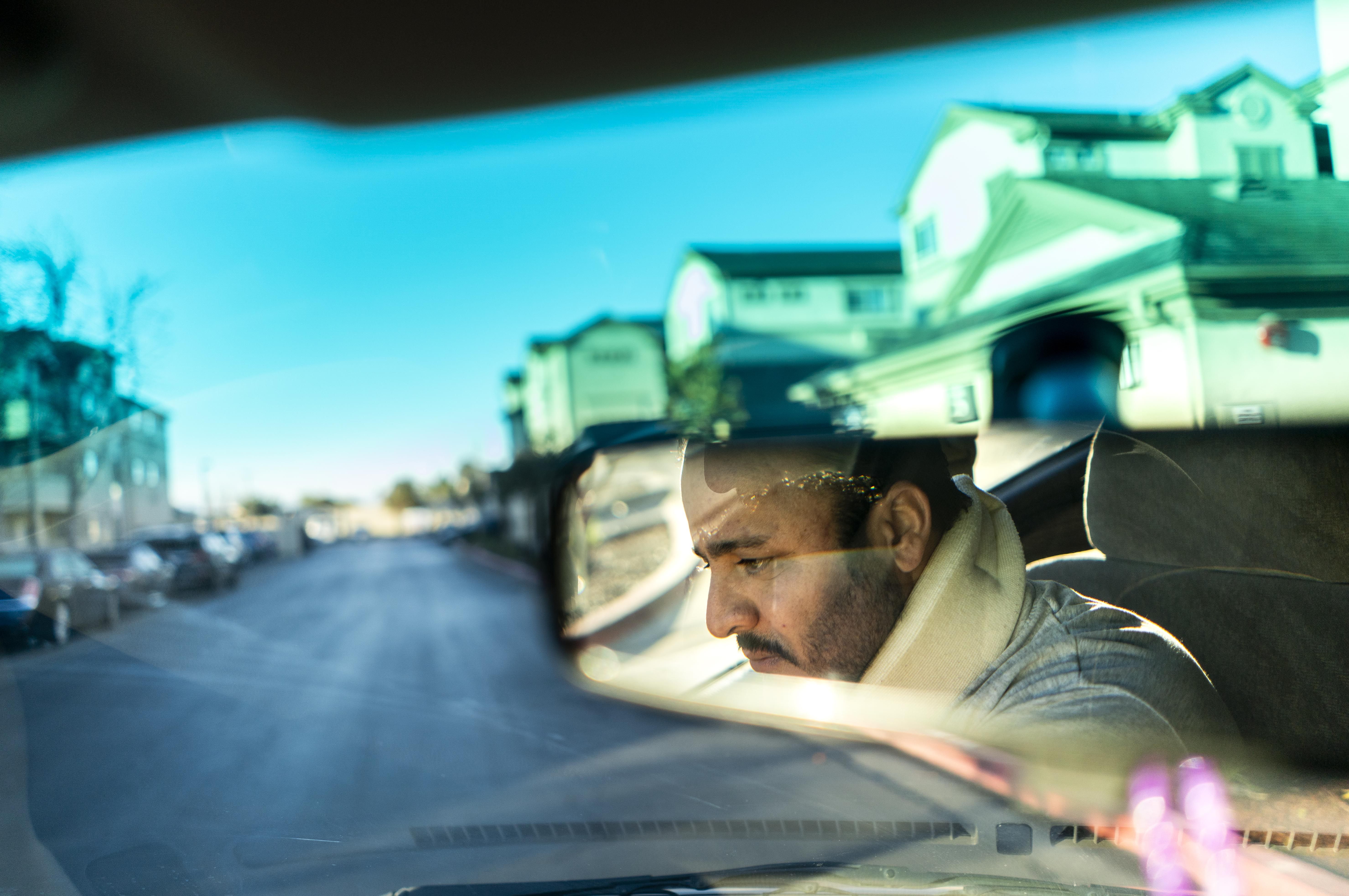A man's reflection in a car windshield. 