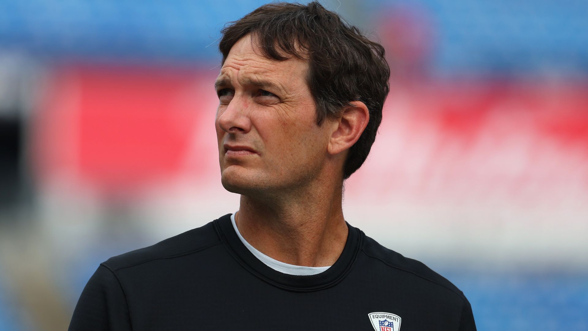 NFL coach Ken Dorsey looks off into the distance.