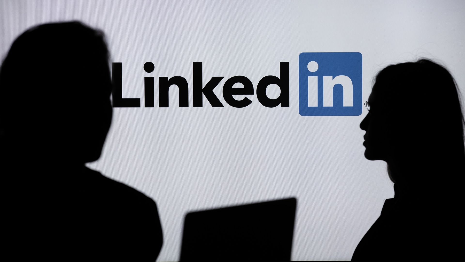 People in a shadow with the LinkedIn logo in the background. 