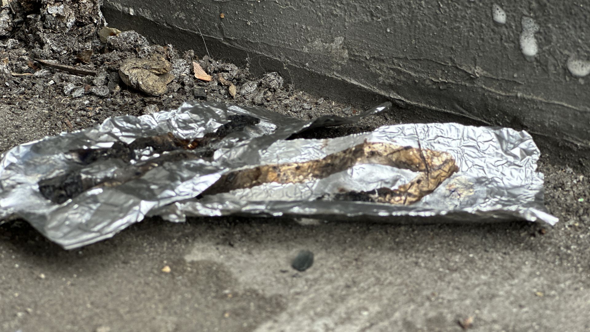 Tin foil on the ground marked with brown lines where opioid pills have been melted and smoked