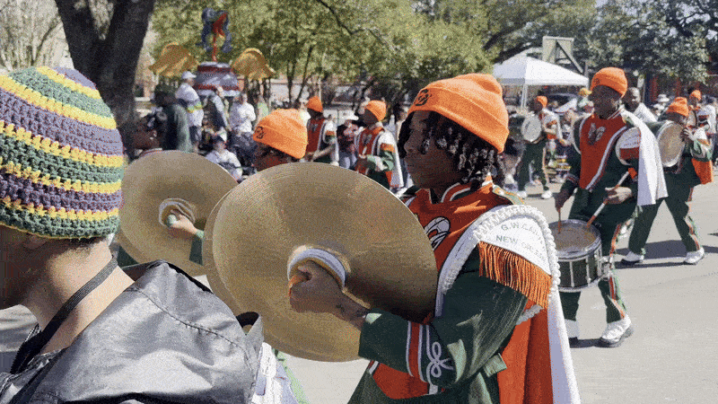 Image shows high school band students marching and playing music.