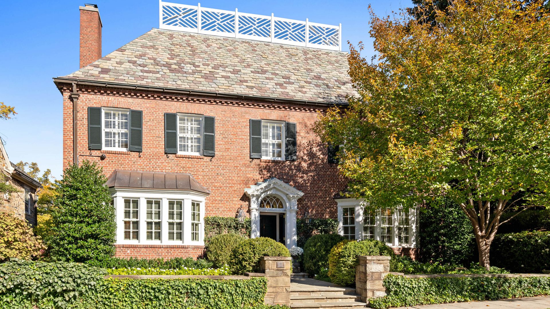 A photo of a large brick home with black shutters.