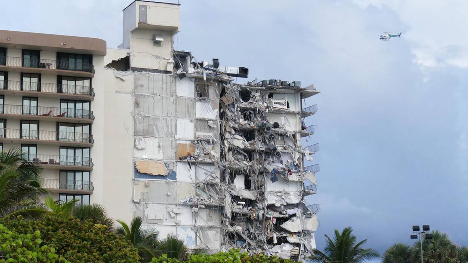 Photo of a collapsed condo building with torn walls and rubble hanging off the exterior