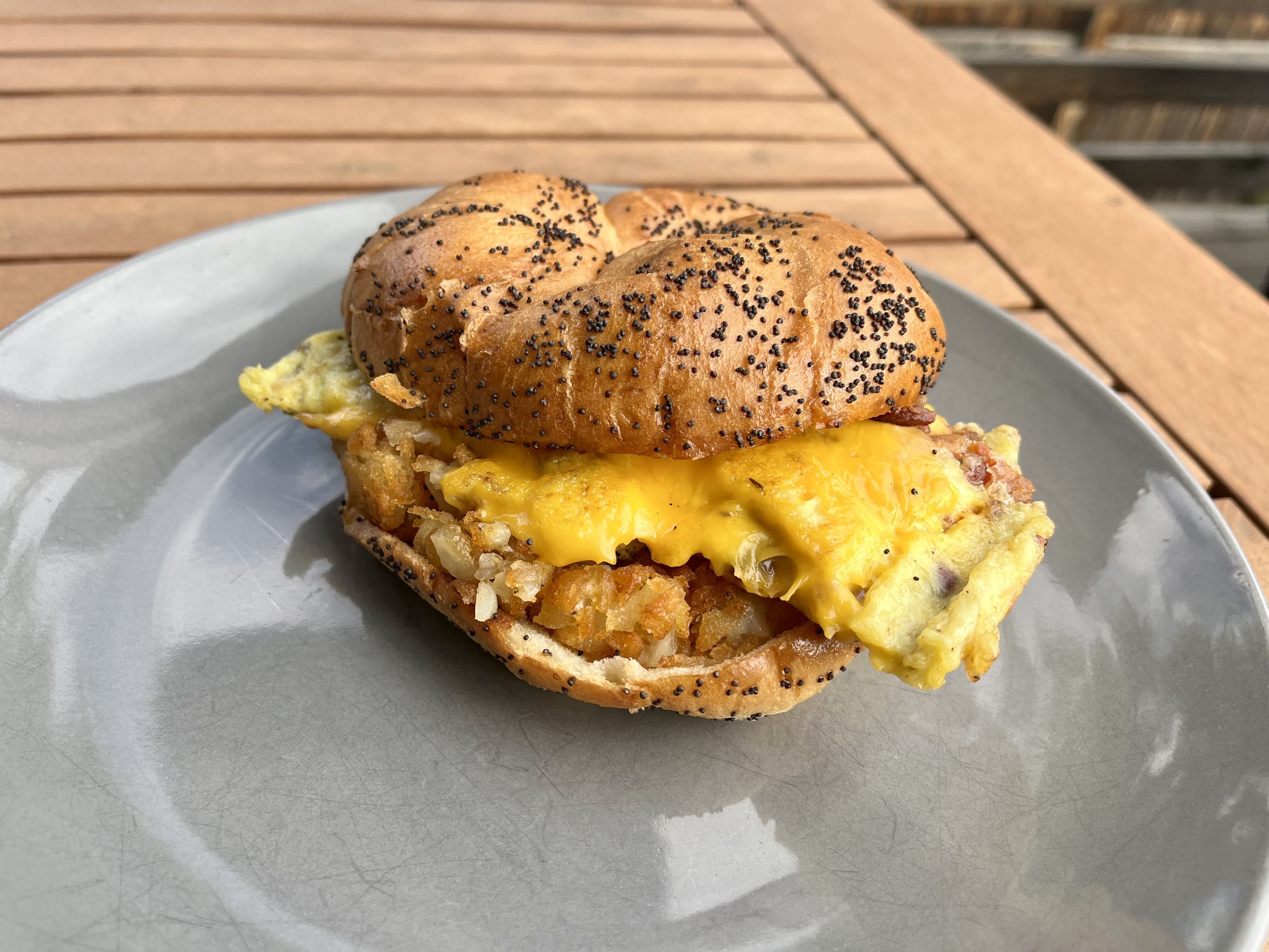 A breakfast sandwich with a poppy seed bagel. 
