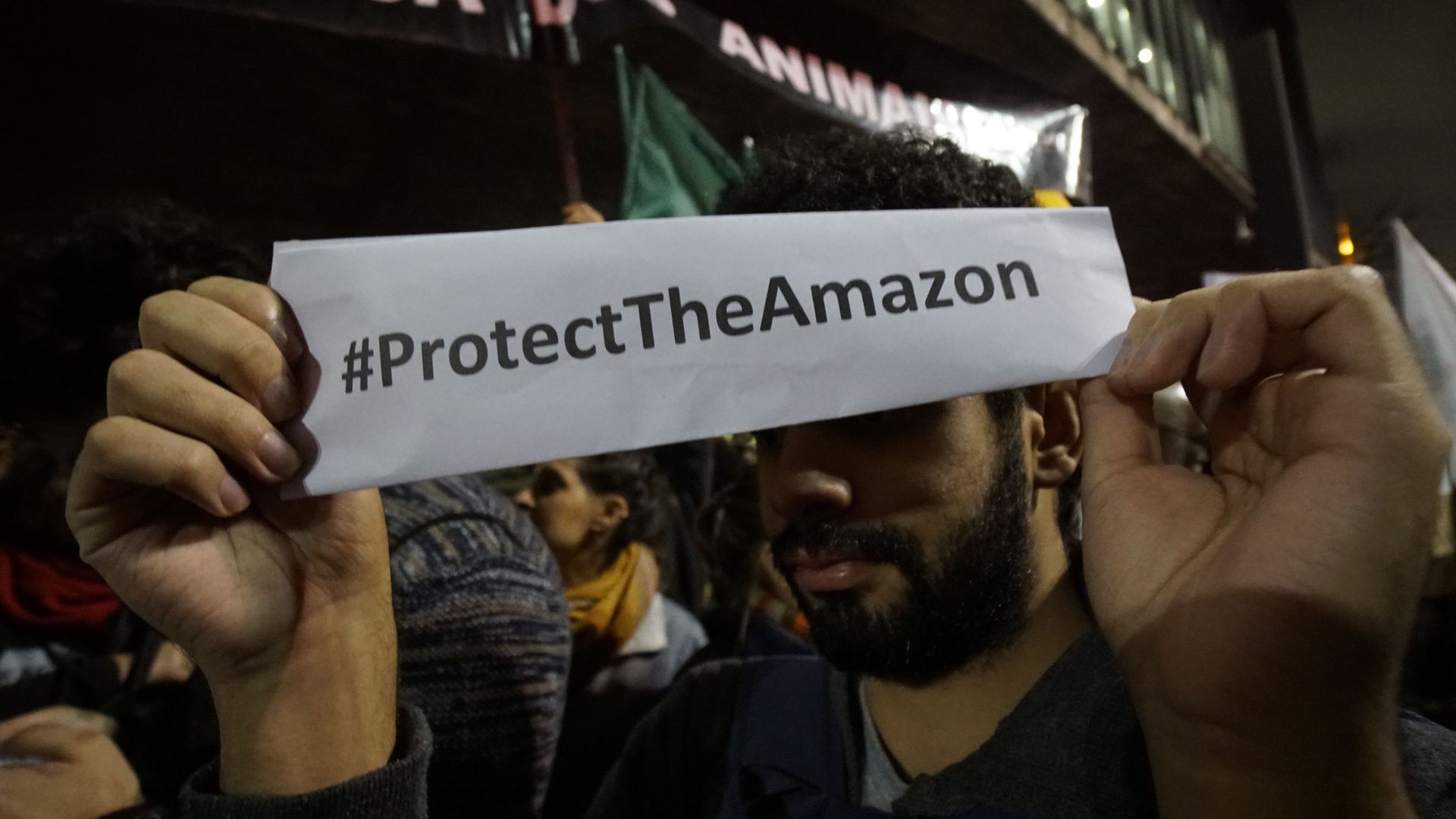 Photo of a person holding a strip of paper that says #ProtectTheAmazon