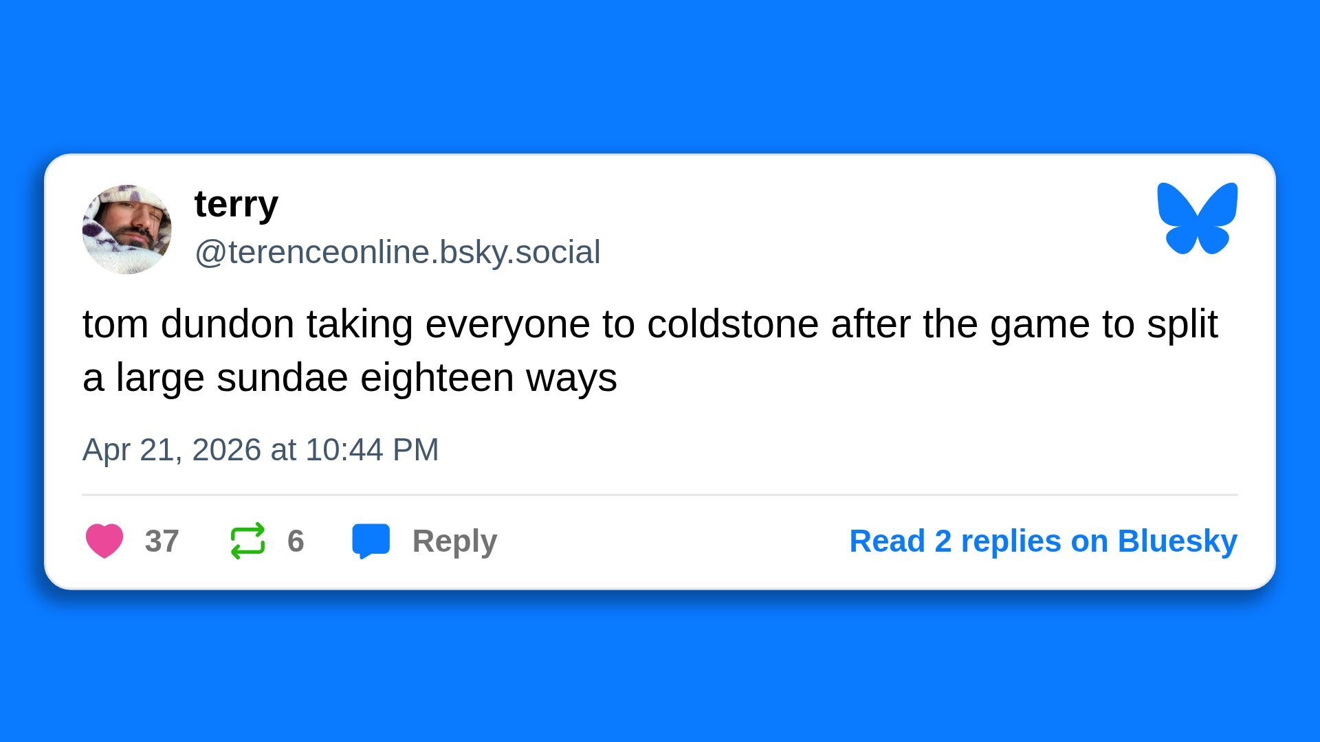 Blue background with a white rounded Bluesky post card. User terry (@terenceonline.bsky.social), round profile photo of a man in a towel, blue butterfly icon on the right. Post about Tom Dundon taking everyone to Cold Stone for a large sundae; Apr 21, 2026 10:44 PM.