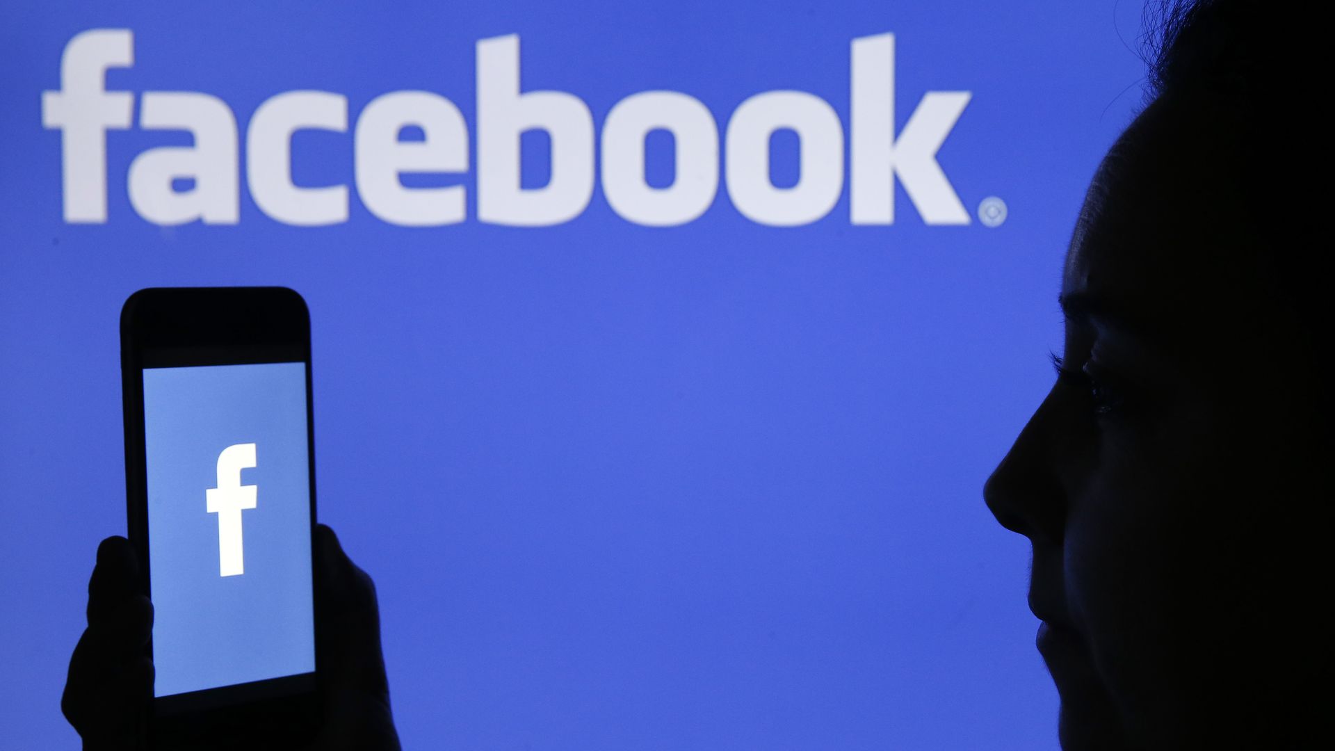 In this image, the Facebook logo is visible on a phone and in the background