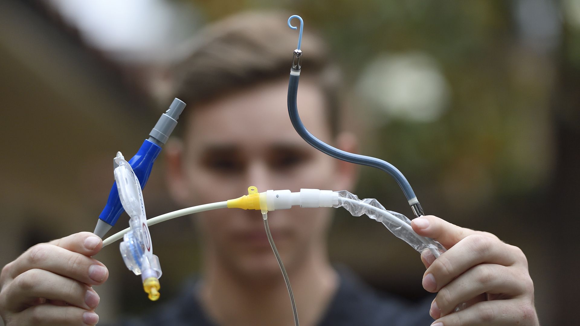 A young man holds up an Impella heart pump.