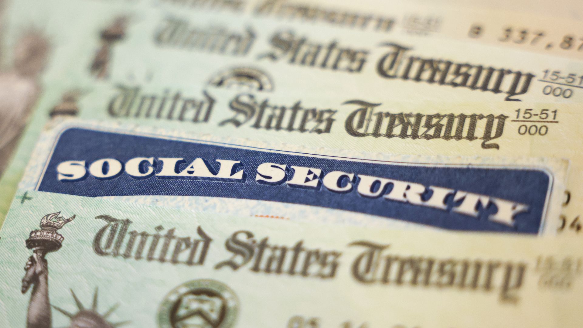 Close-up of several paper documents including a Social Security card with a blue header and multiple United States Treasury checks in light green and beige colors.