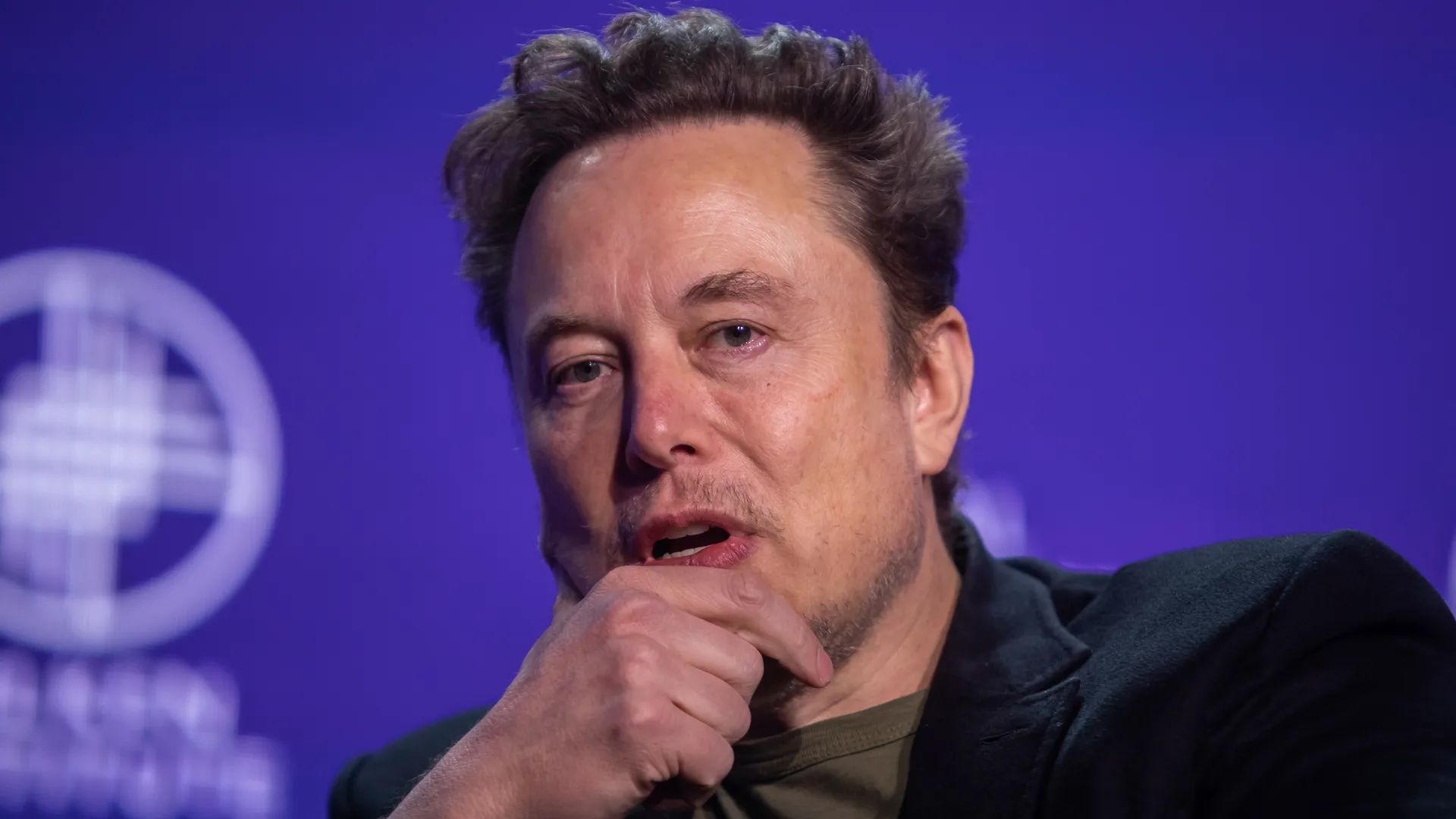 Photo of Elon Musk speaking with his right hand on his chin