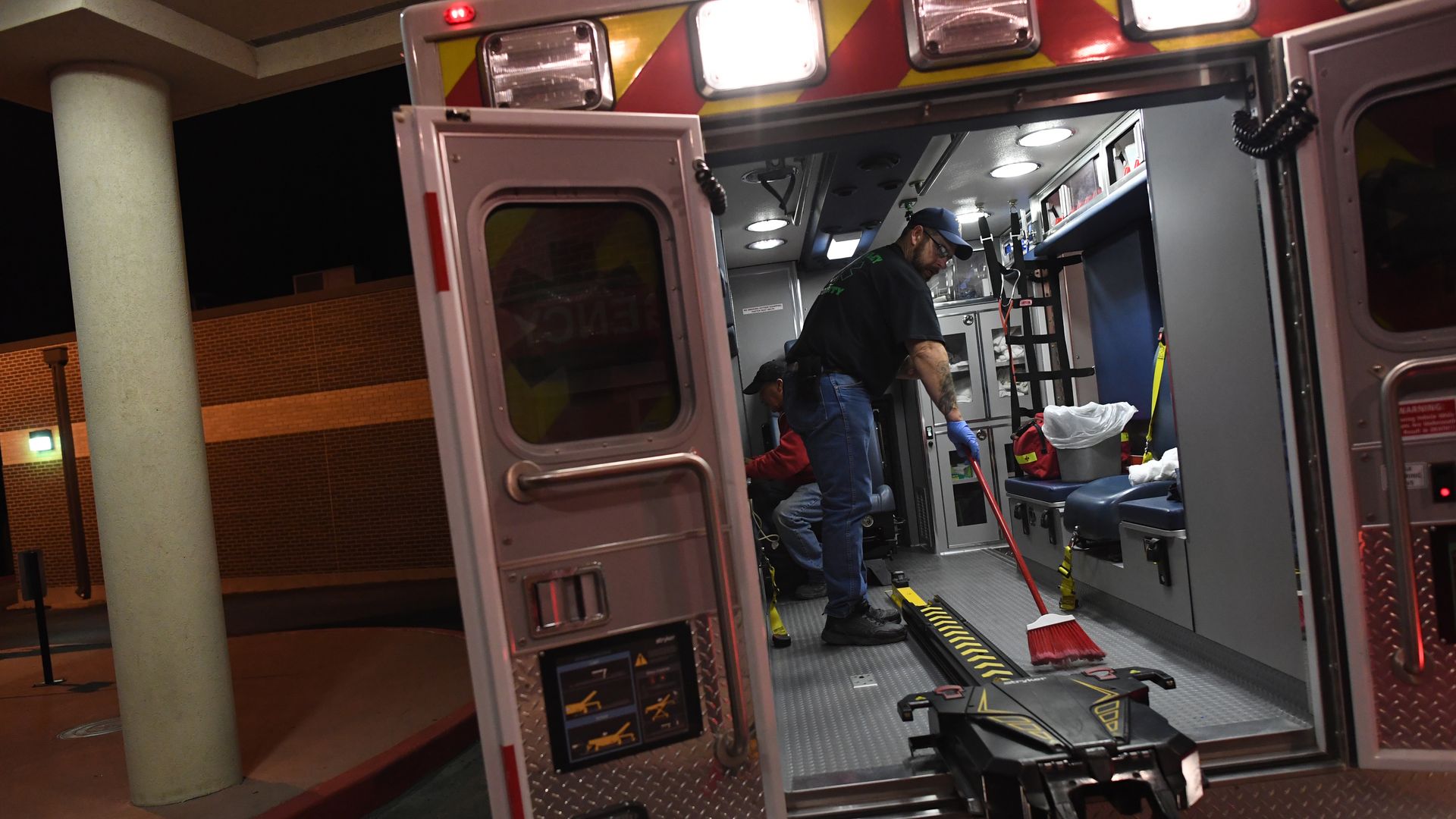 A man sweeps out the back of an ambulance.