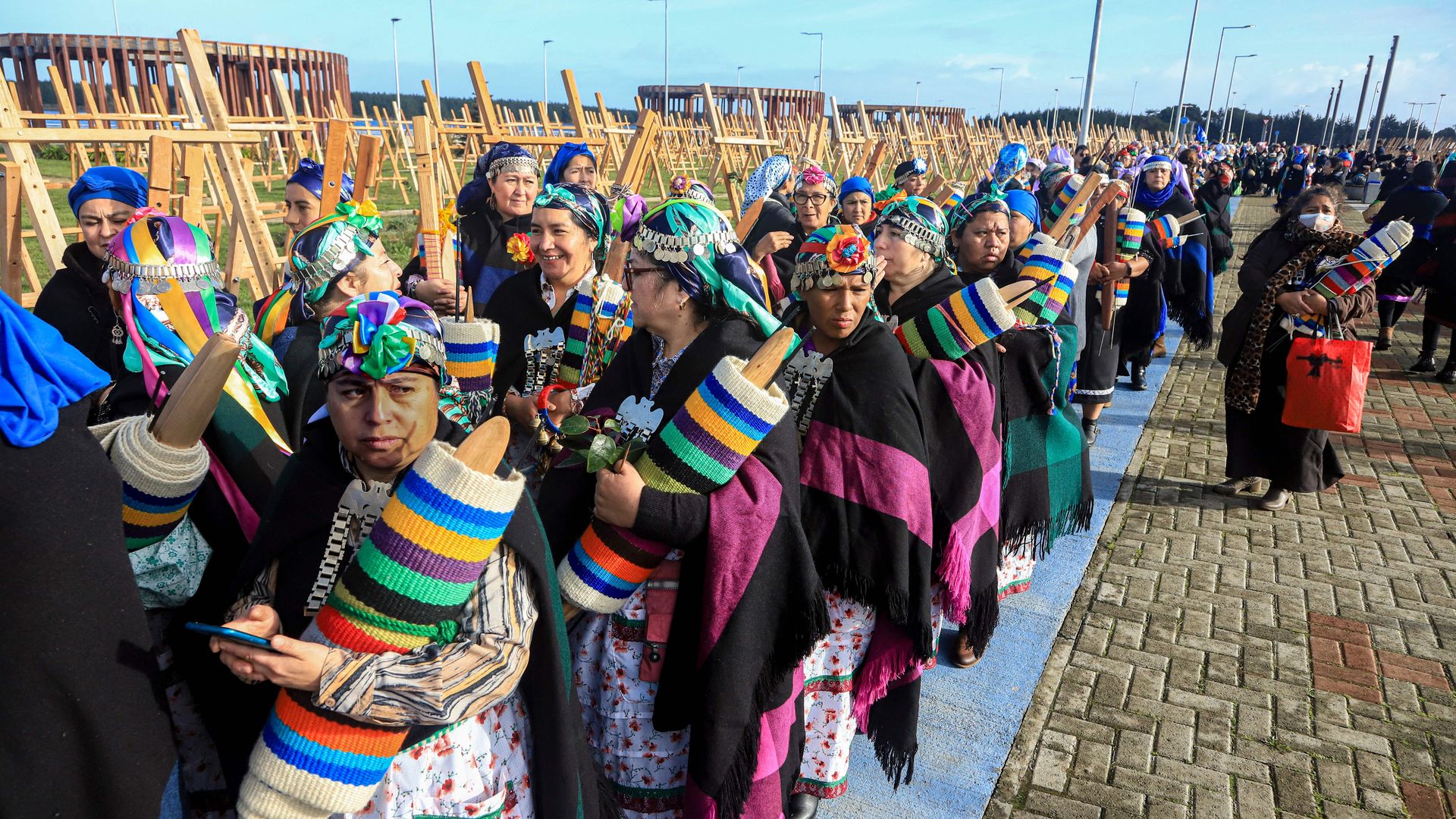 Chilean Mapuche weavers are lined up while holding rows of fabric to weave