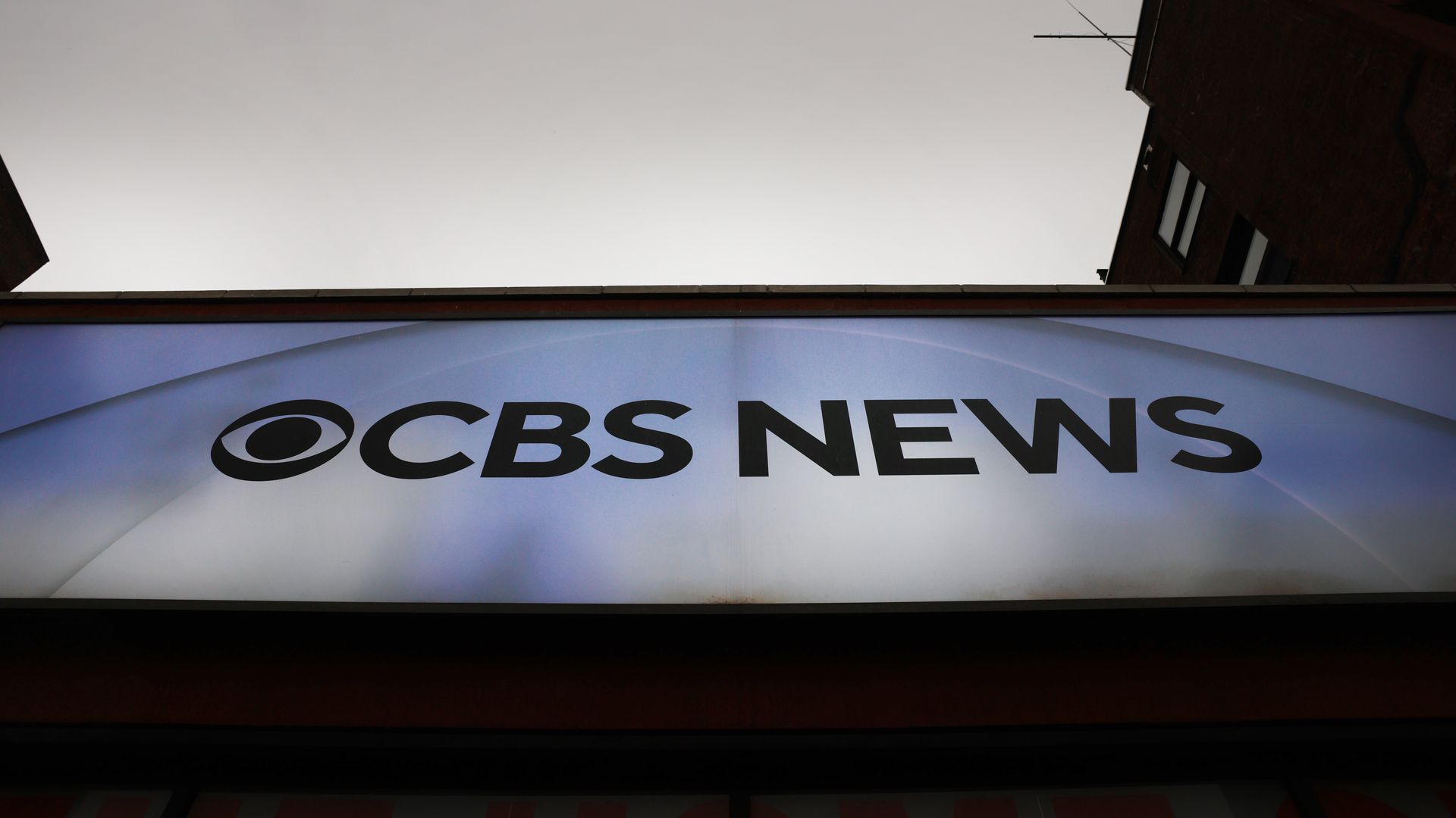 A large storefront sign reading "CBS News" with the CBS eye logo on a blue gradient background.