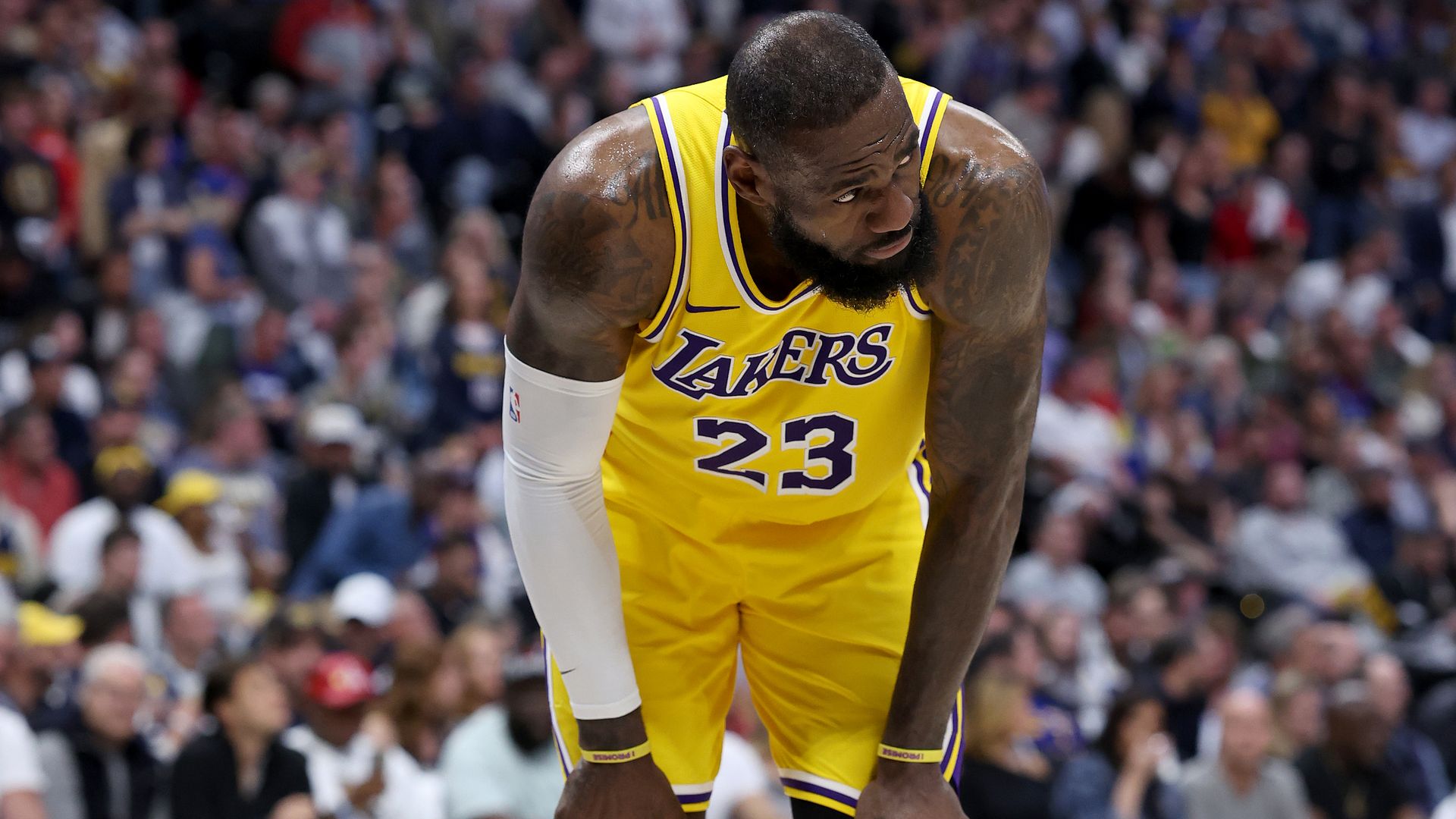 LeBron James with hands on his knees in yellow Lakers jersey
