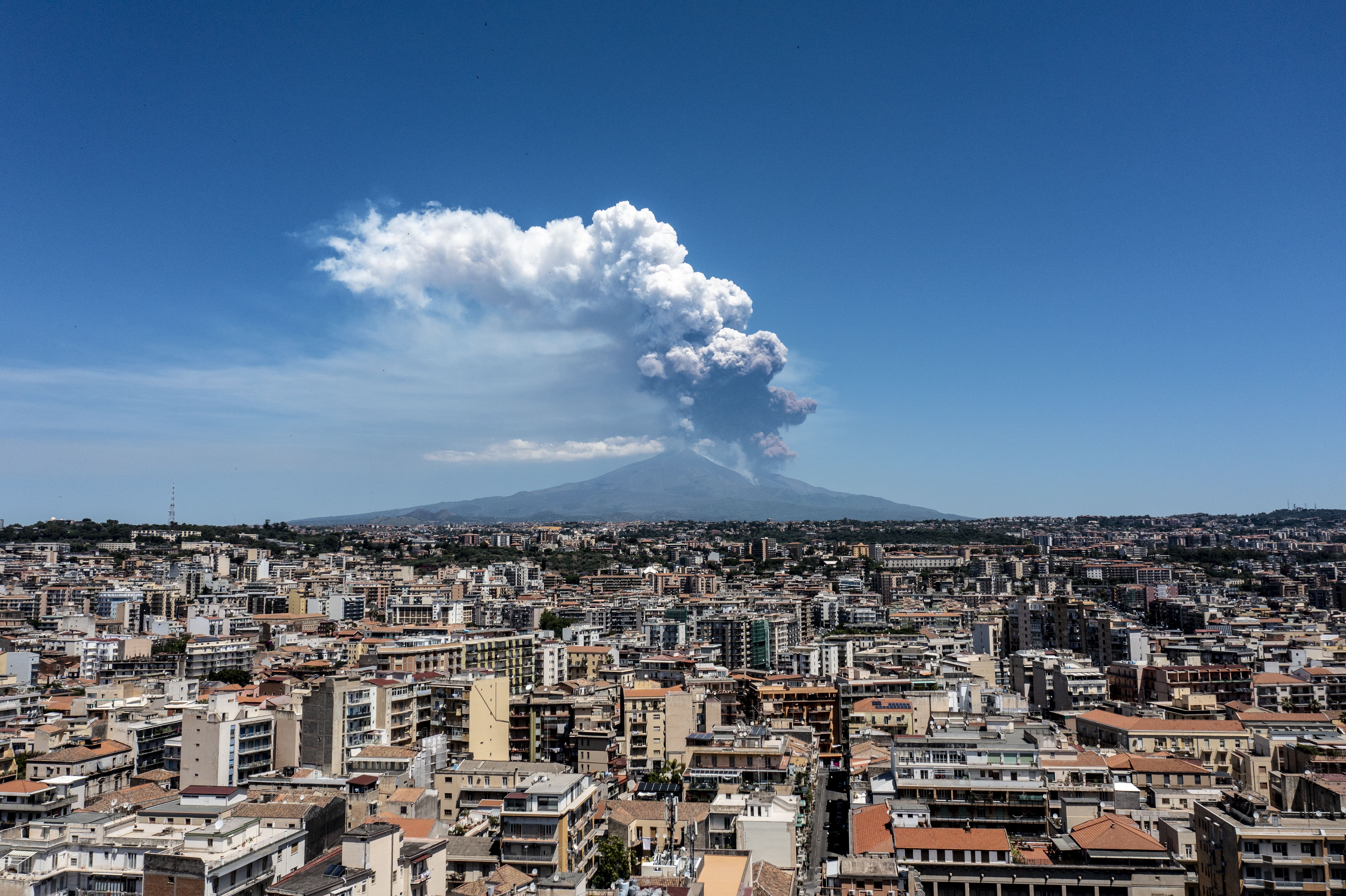 CATANIA, ITALY - JUNE 02: Mount Etna exhibits a Strombolian eruption, with a volcanic plume rising from the southeast crater, on June 02, 2025 in Catania, Italy. An orange aviation warning has been issued. The images show aerial views of the volcano with the city of Catania in the background. (Photo