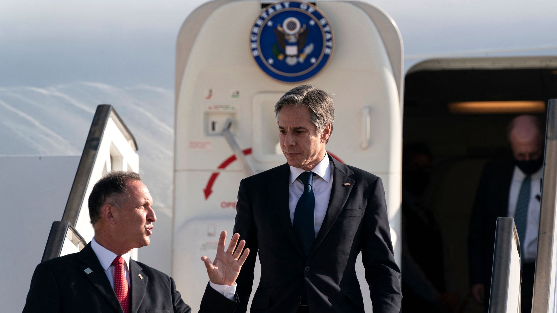 Secretary of State Antony Blinken (C) is greeted by Israeli Chief of State Protocol Gil Haskelas, as he steps off the plane upon arrival at Tel Aviv Ben Gurion Airport, May 25