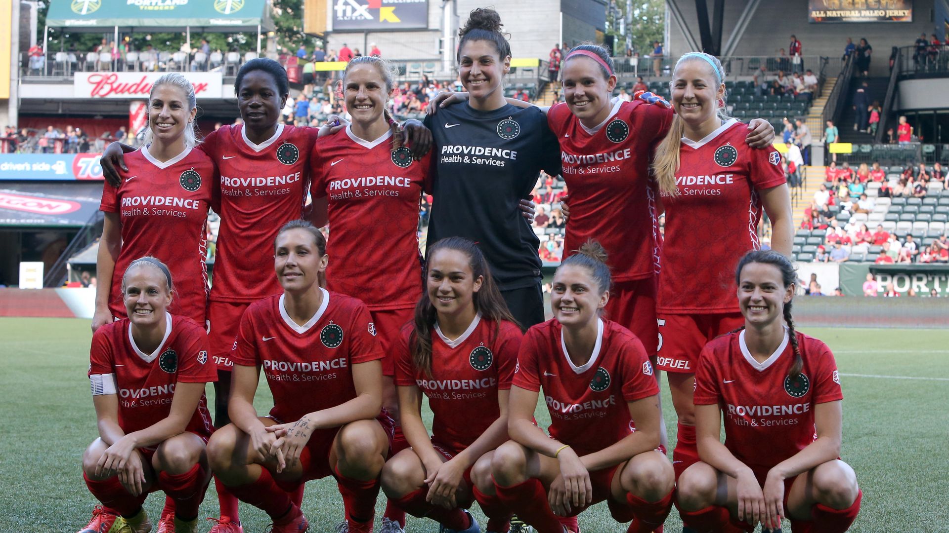 A group photo shows ten players for the Portland Thorns posing together on a soccer field.