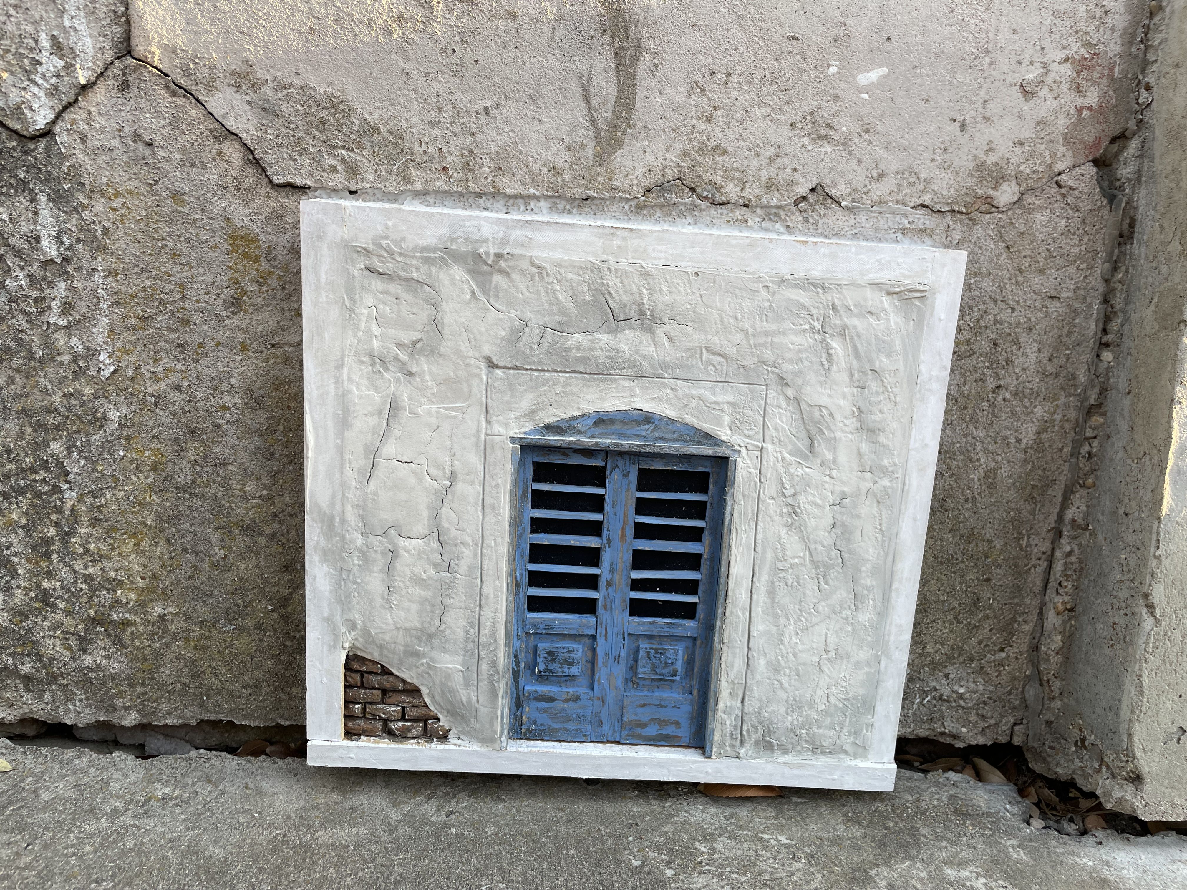 A tiny blue door at the bottom of stone wall