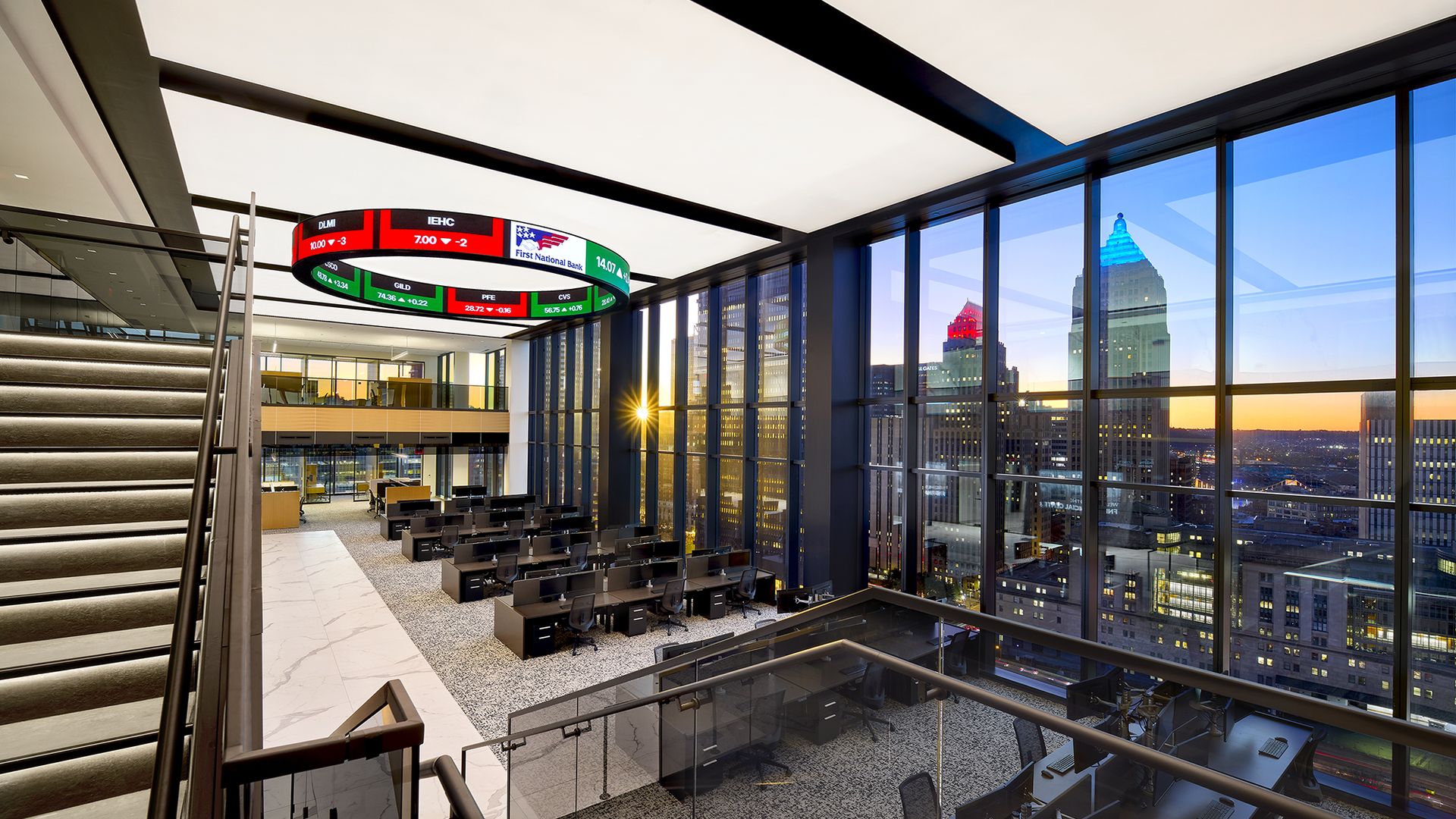 An office lobby of a building with floor to ceiling windows and a sunset view of the Pittsburgh skyline.