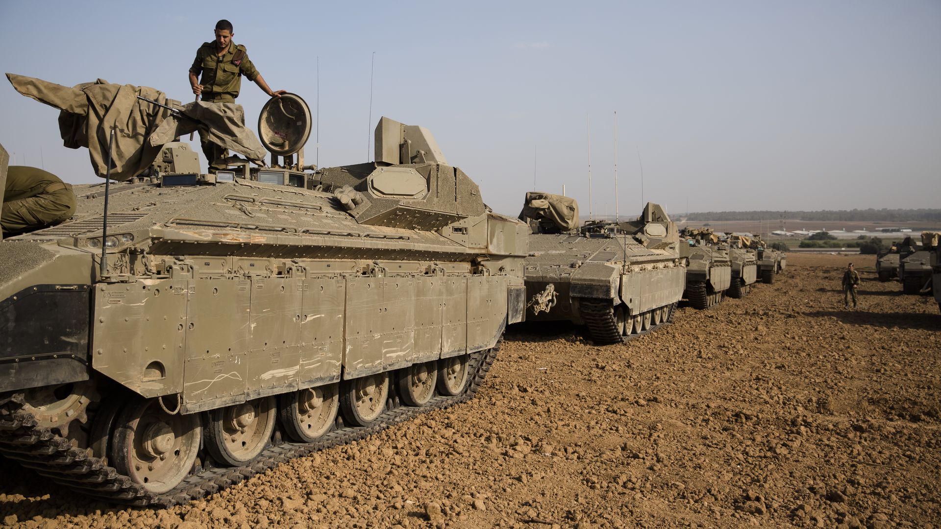 An  Israeli soldier stands on top an armoured personnel carrier near the border with Gaza