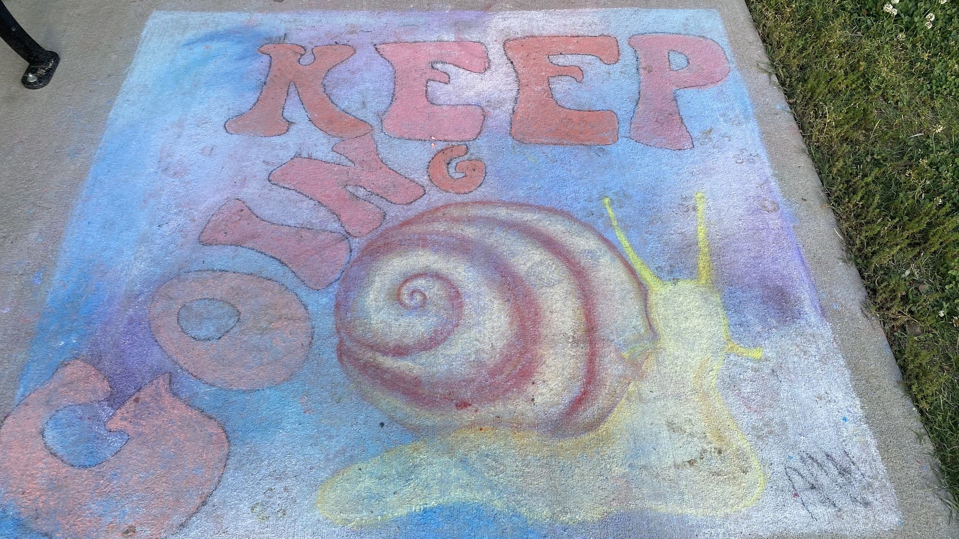 A sidewalk chalk drawing of a snail reading "Keep Going."