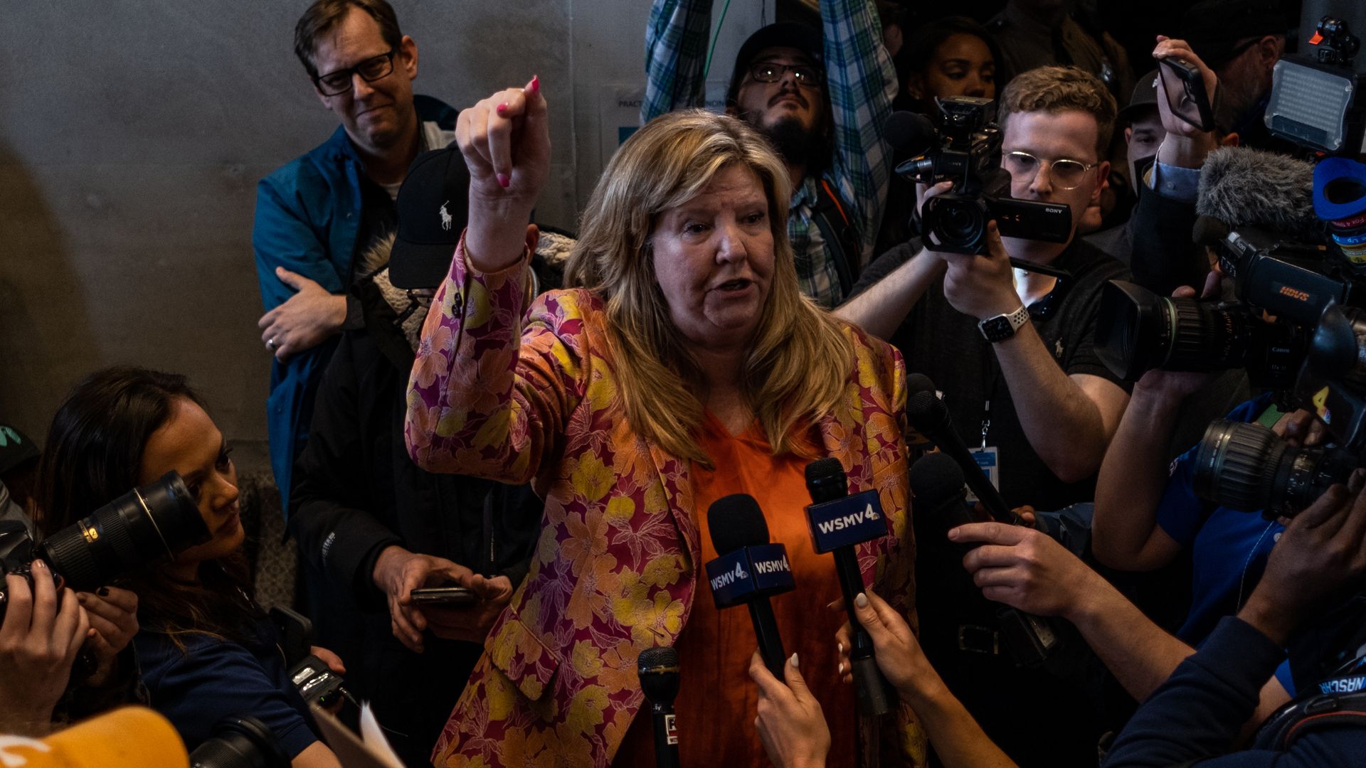 Gloria Johnson surrounded by reporters with microphones.