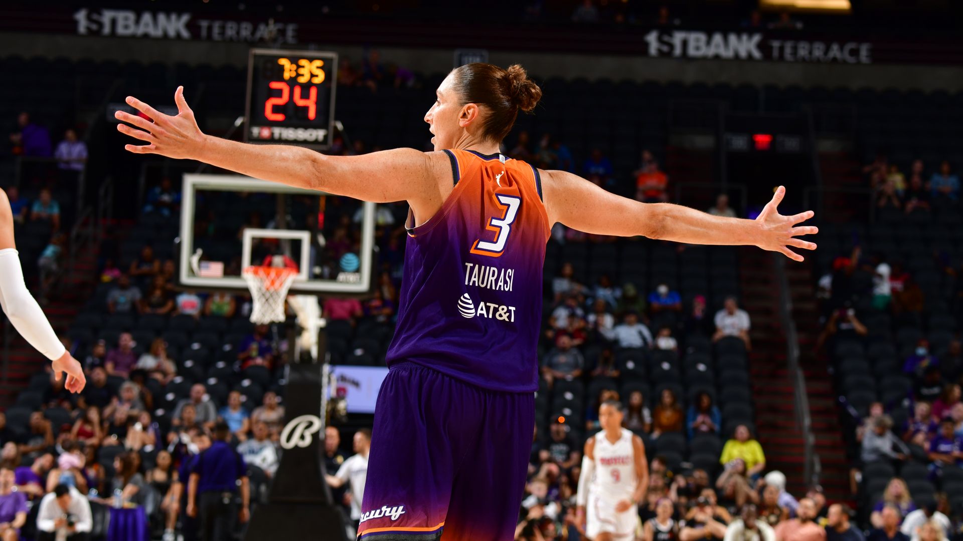 Diana Taurasi stands on the basketball court with her arms stretched out to her side. 