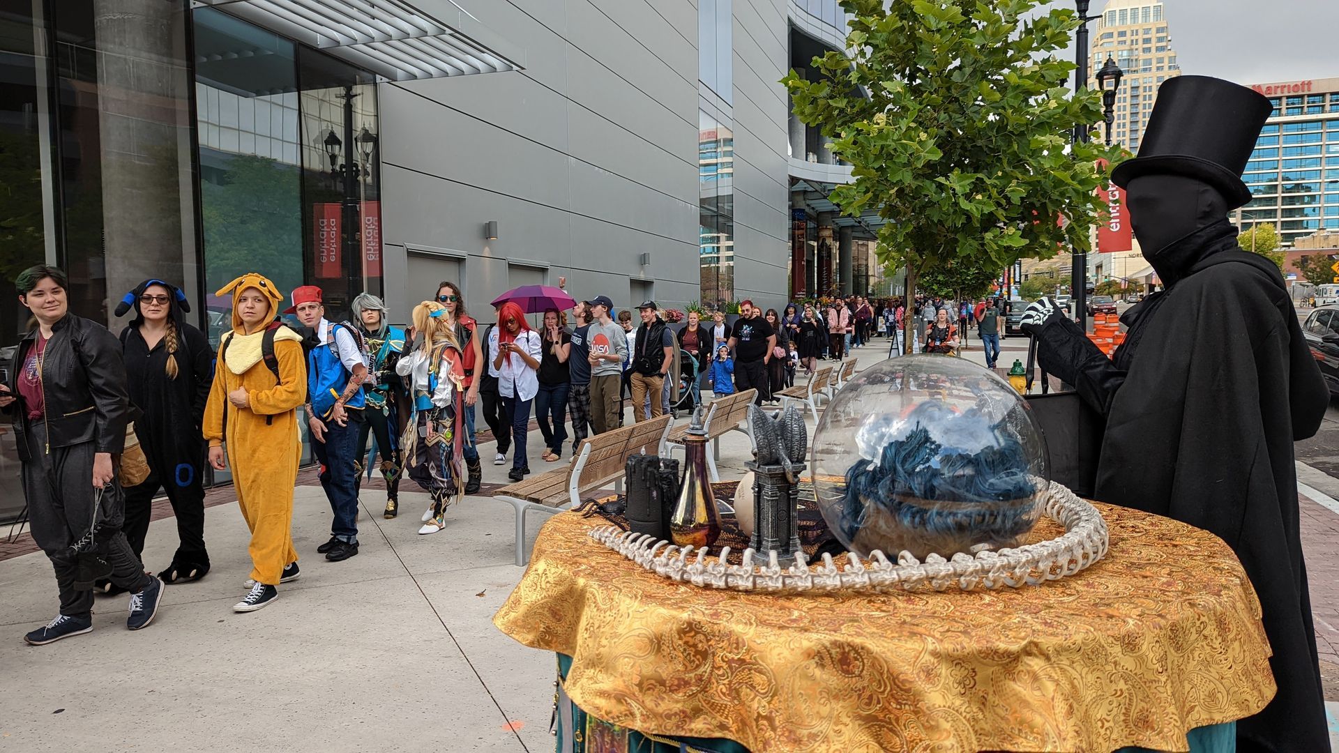 Cosplayers line up near a magician on a city street