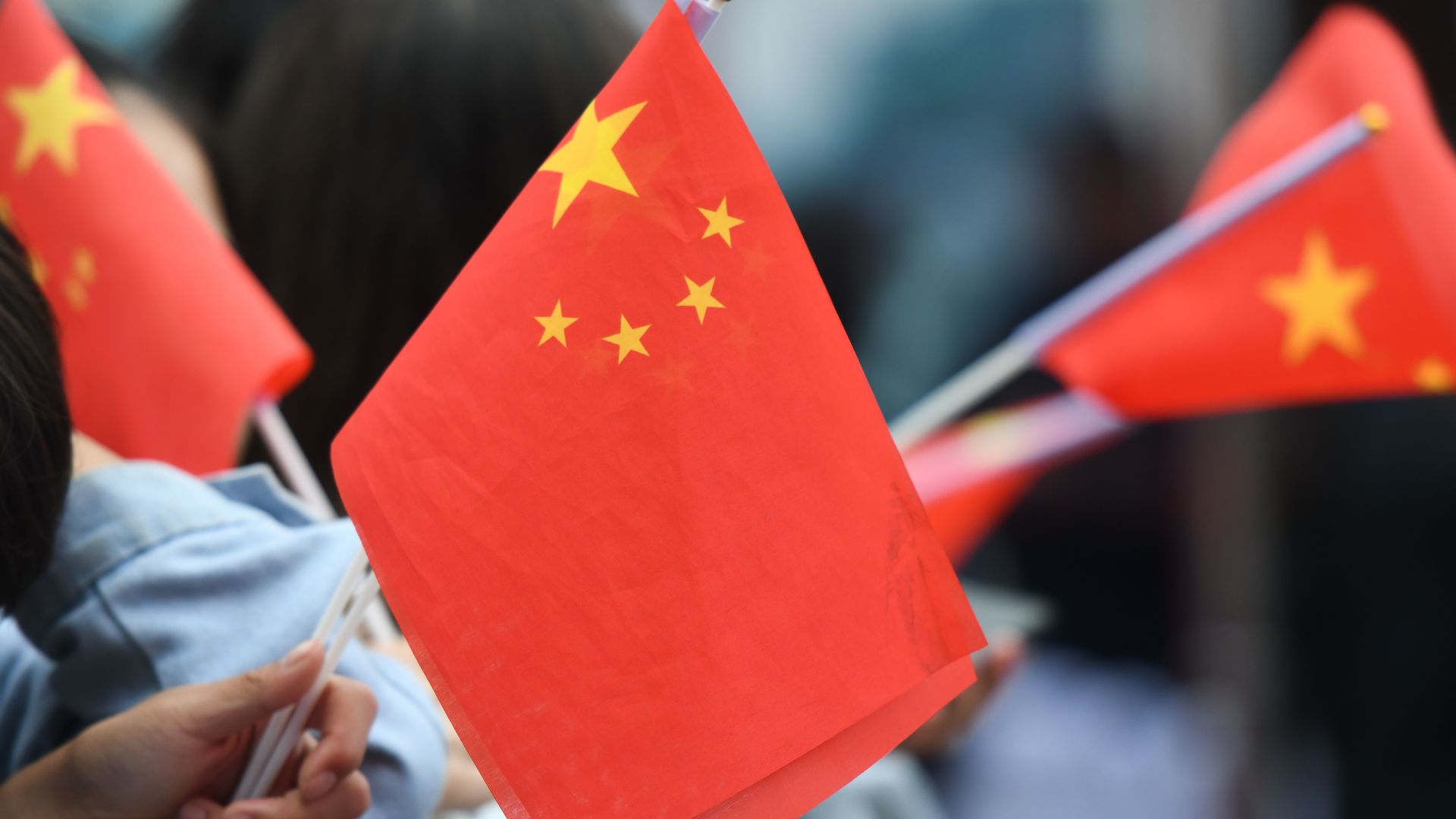 People wave miniature Chinese flags.