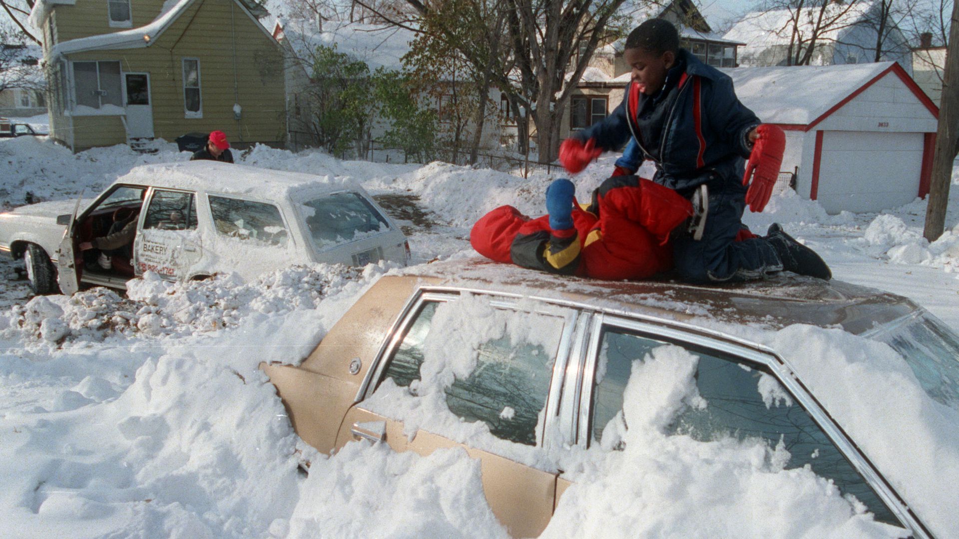 Kids play on top of cars covered in snow during the Halloween Blizzard of 1991.