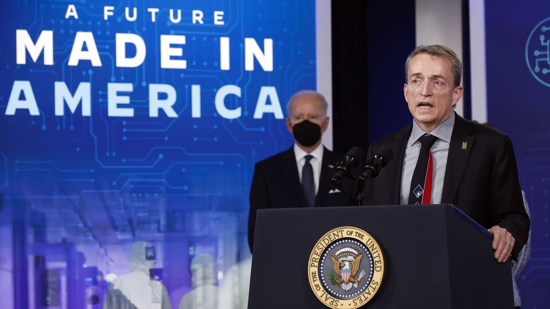 Intel CEO Patrick Gelsinger at a presidential lectern as President Joe Biden looks on. A wall poster reads "A Future Made in America."