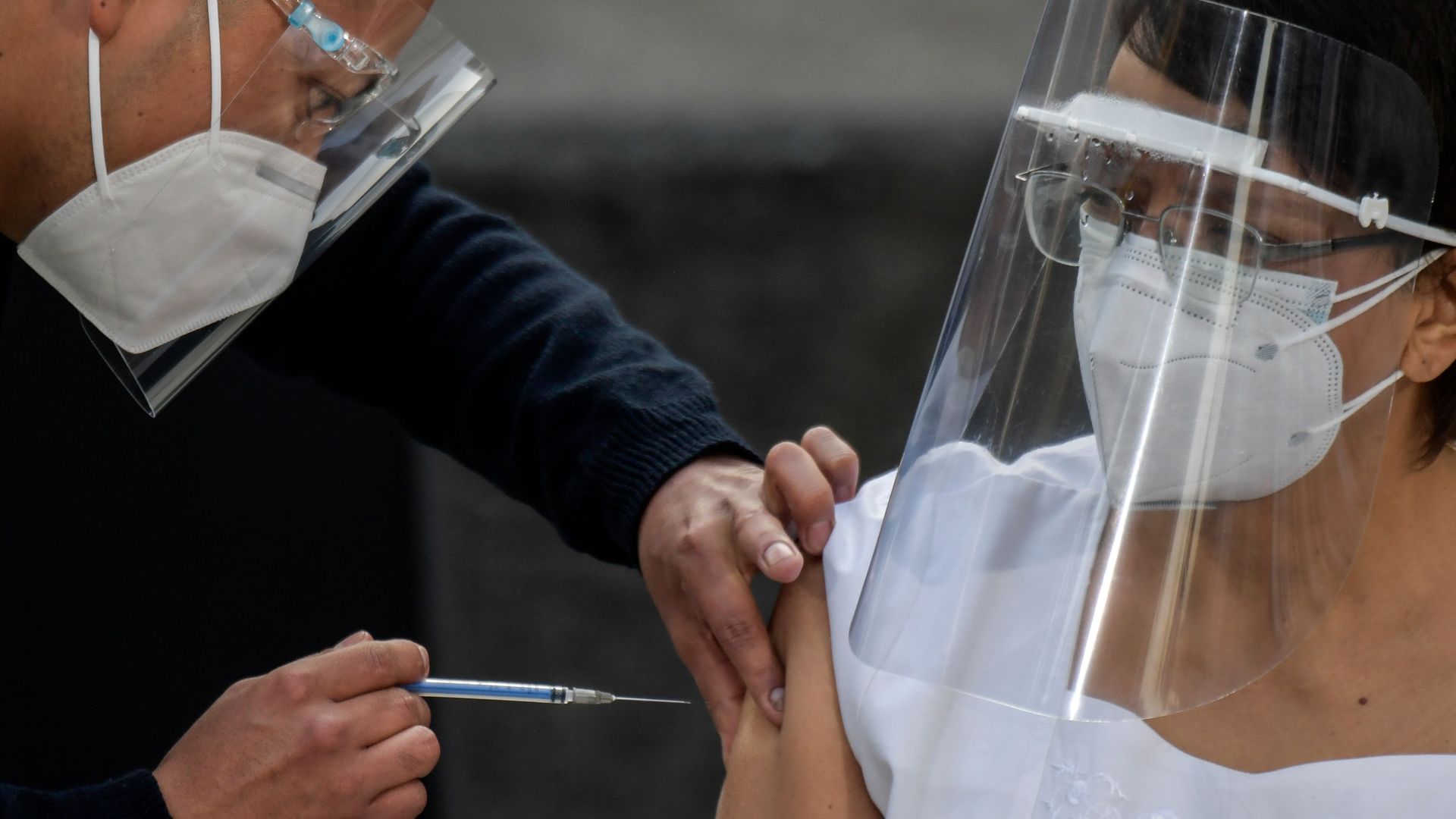 Photo of a masked nurse getting the vaccine