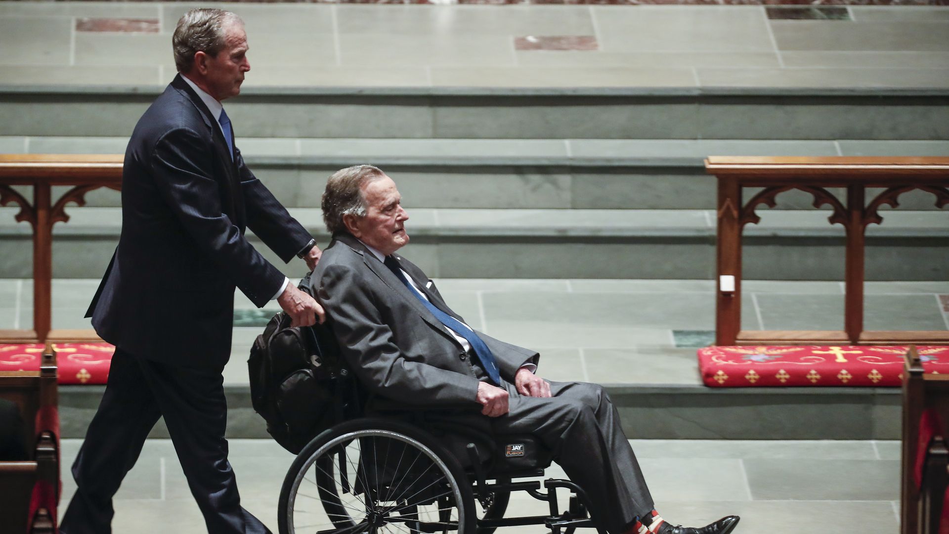 Former president George W. Bush pushes his father, George H.W. Bush, in a wheelchair at Barbara Bush's funeral
