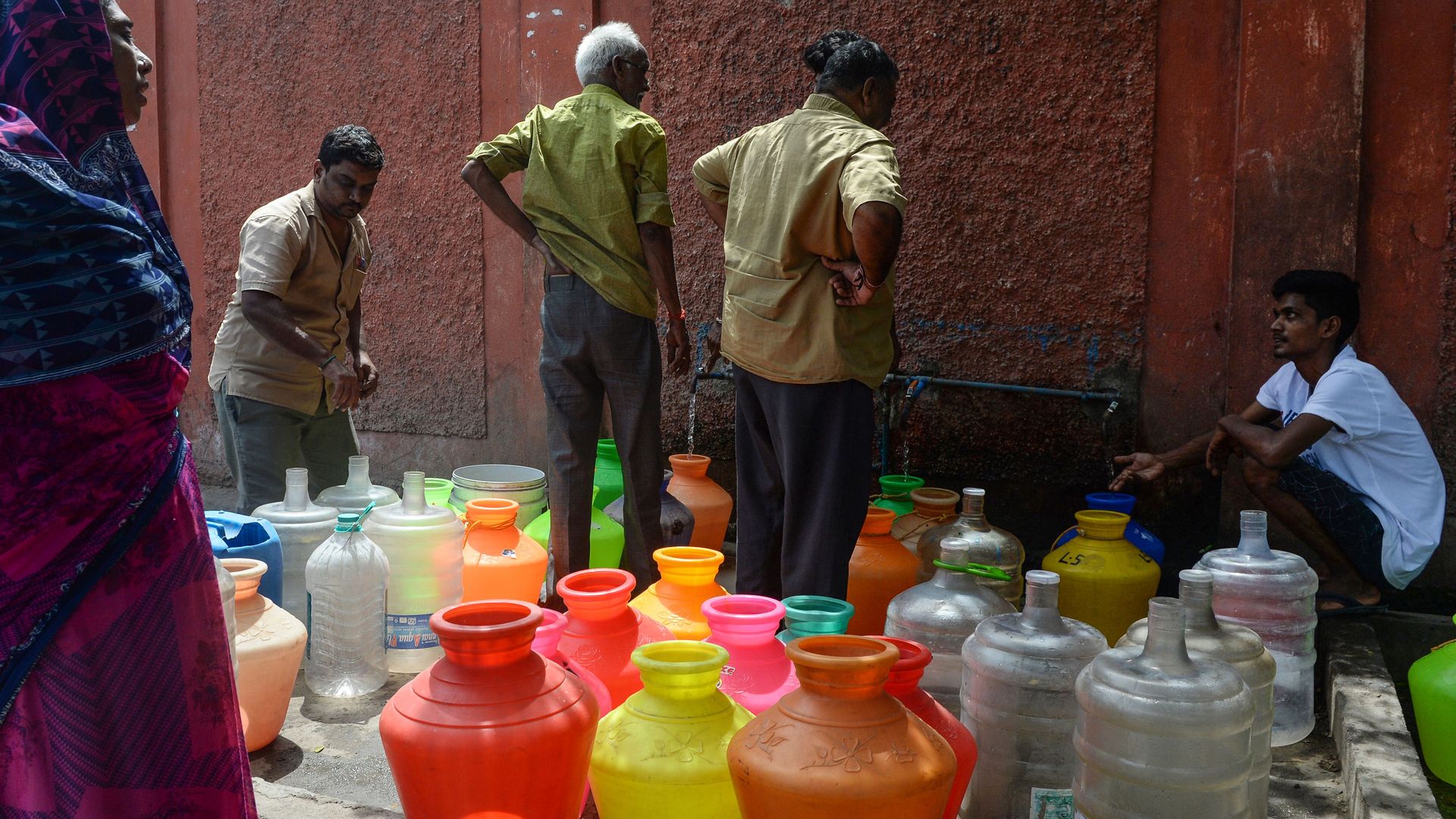 People gather around jugs of water.