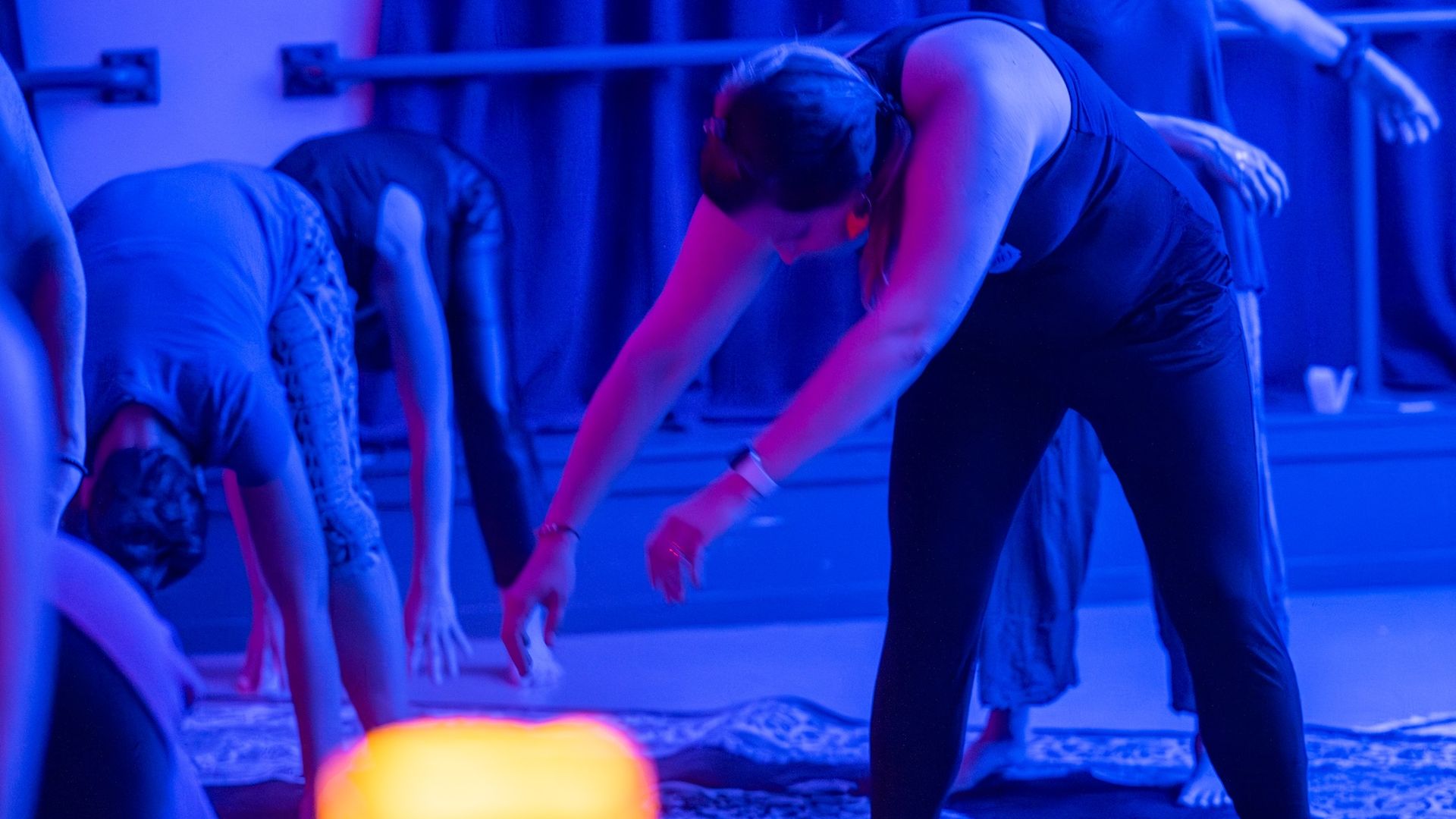 A woman in exercise clothes bending over in a blue-hued room.