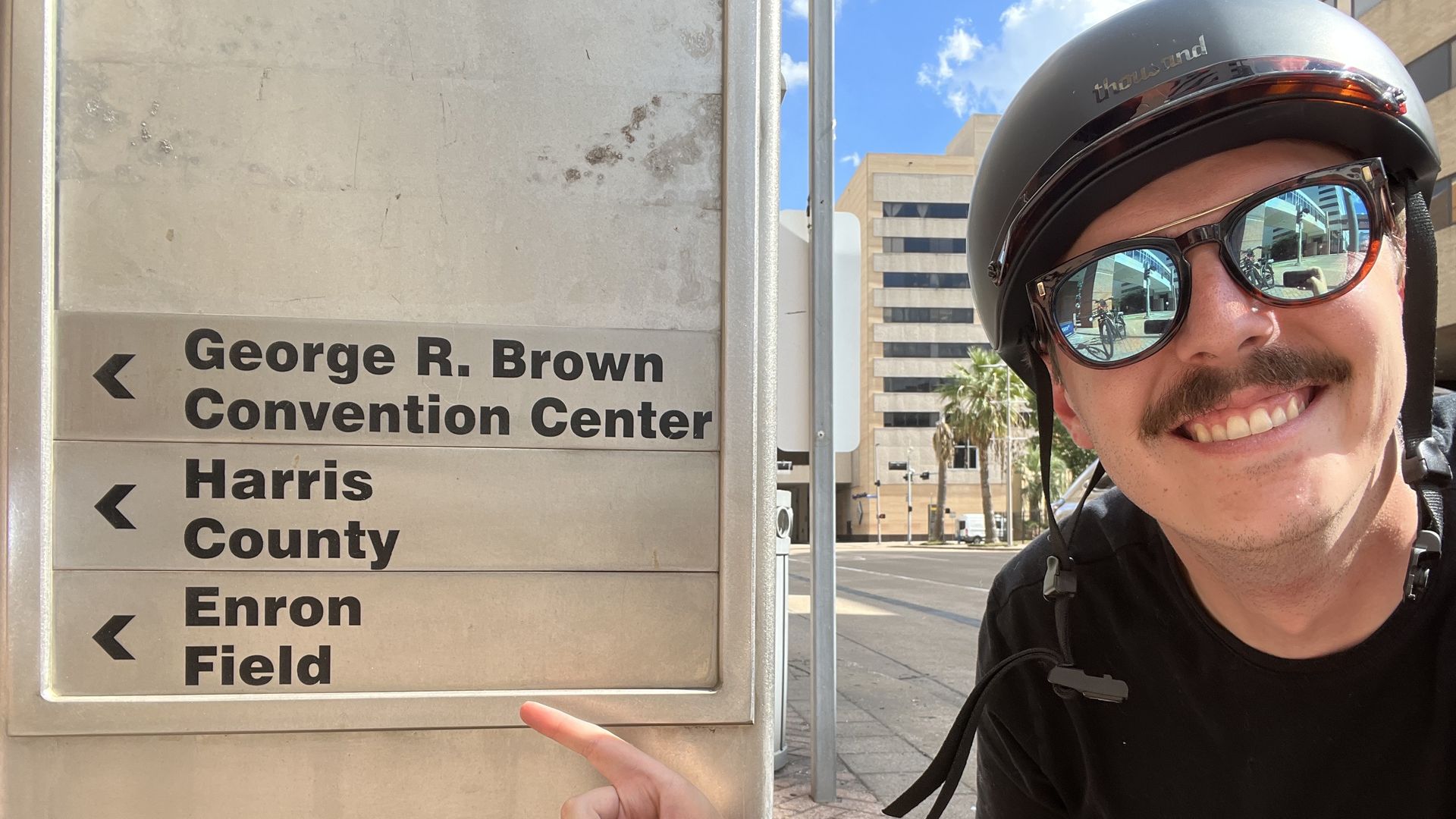 Jay points to a sign that says "Enron Field" in downtown Houston