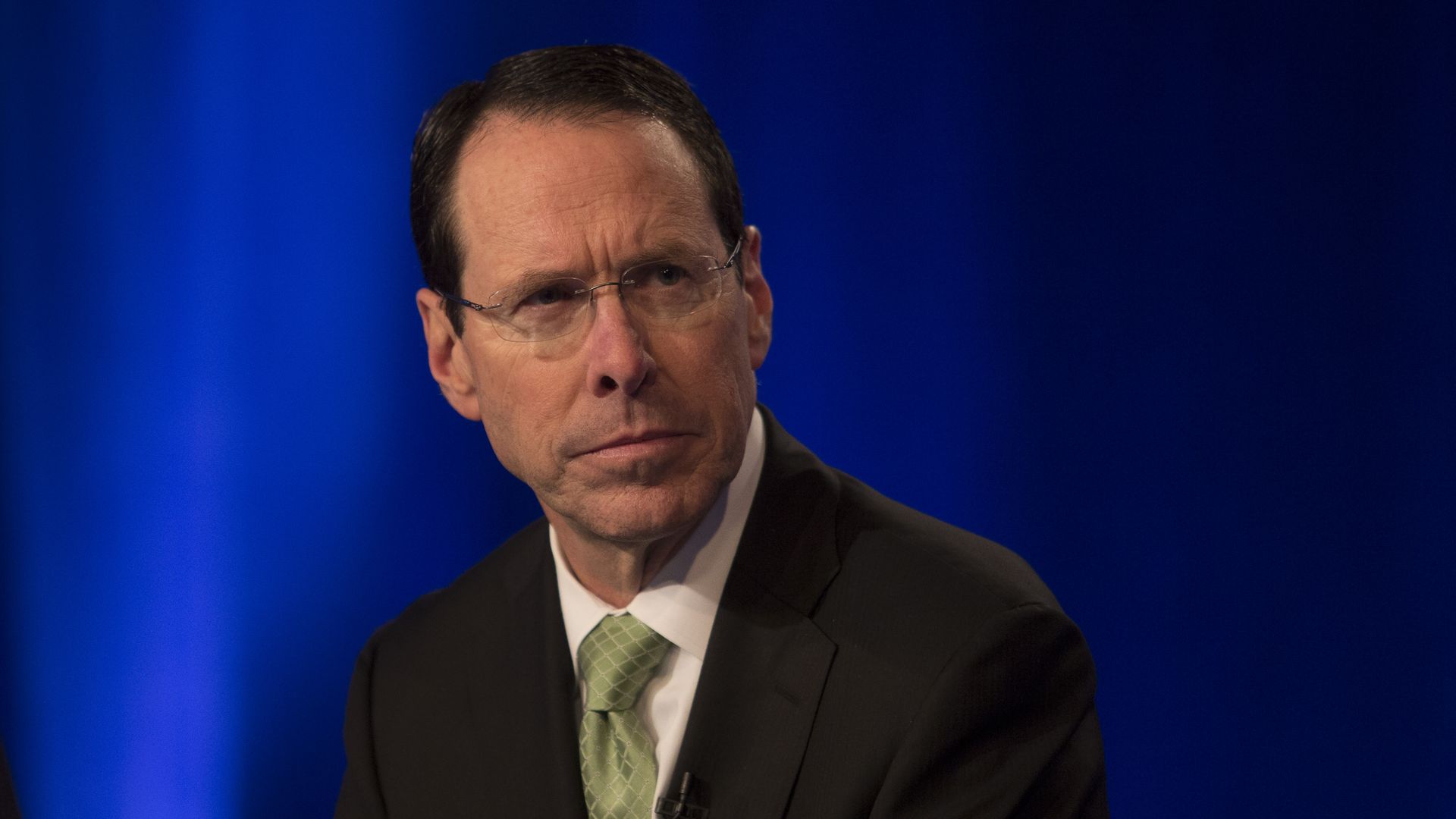 AT&T CEO Randall Stephenson sits in front of a blue backdrop