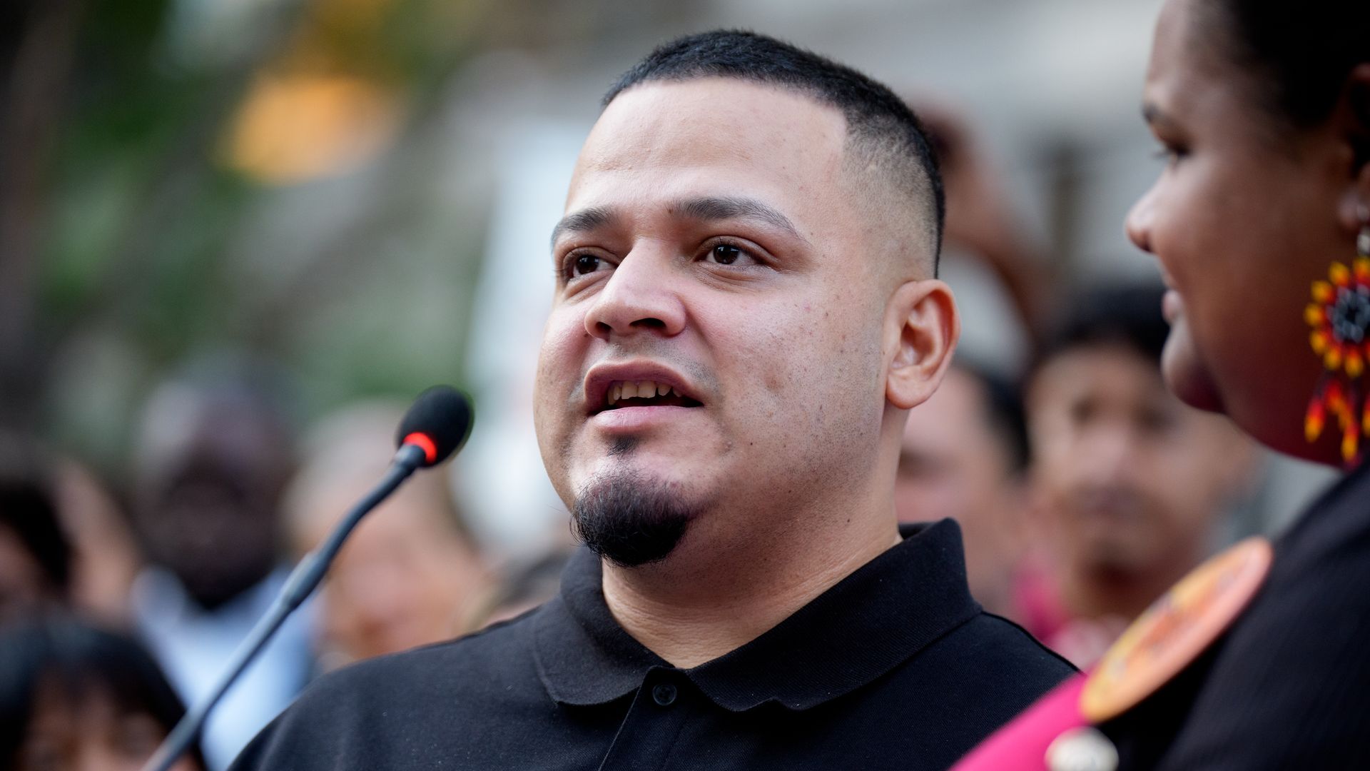 Abrego Garcia wears a black collared shirt and speaks into a microphone
